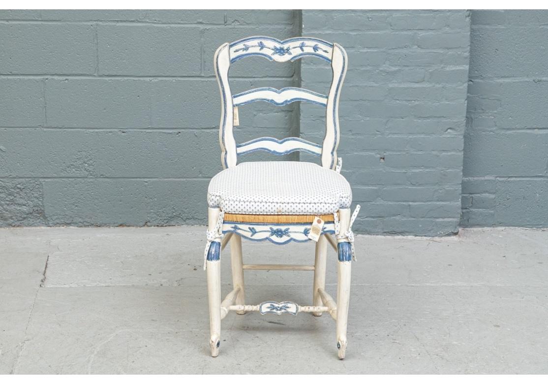 A set of ten Louis XV provincial style white and blue painted dining chairs, 20th century. 
Standing on four legs with hand rush seat and further enhanced for comfort with fitted and tied, seat cushions. 
Serpentine form, ladder back frame with