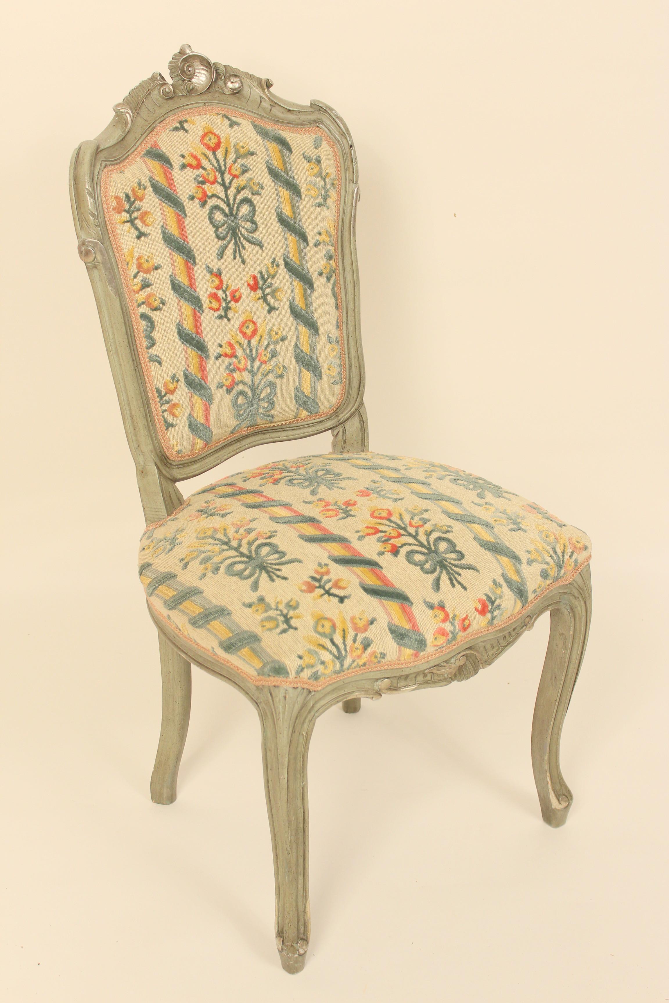 Set of 10 grayish green painted Louis XV style dining room chairs with silver highlights, circa late 20th century. Embroidered style upholstery with slightly raised areas.