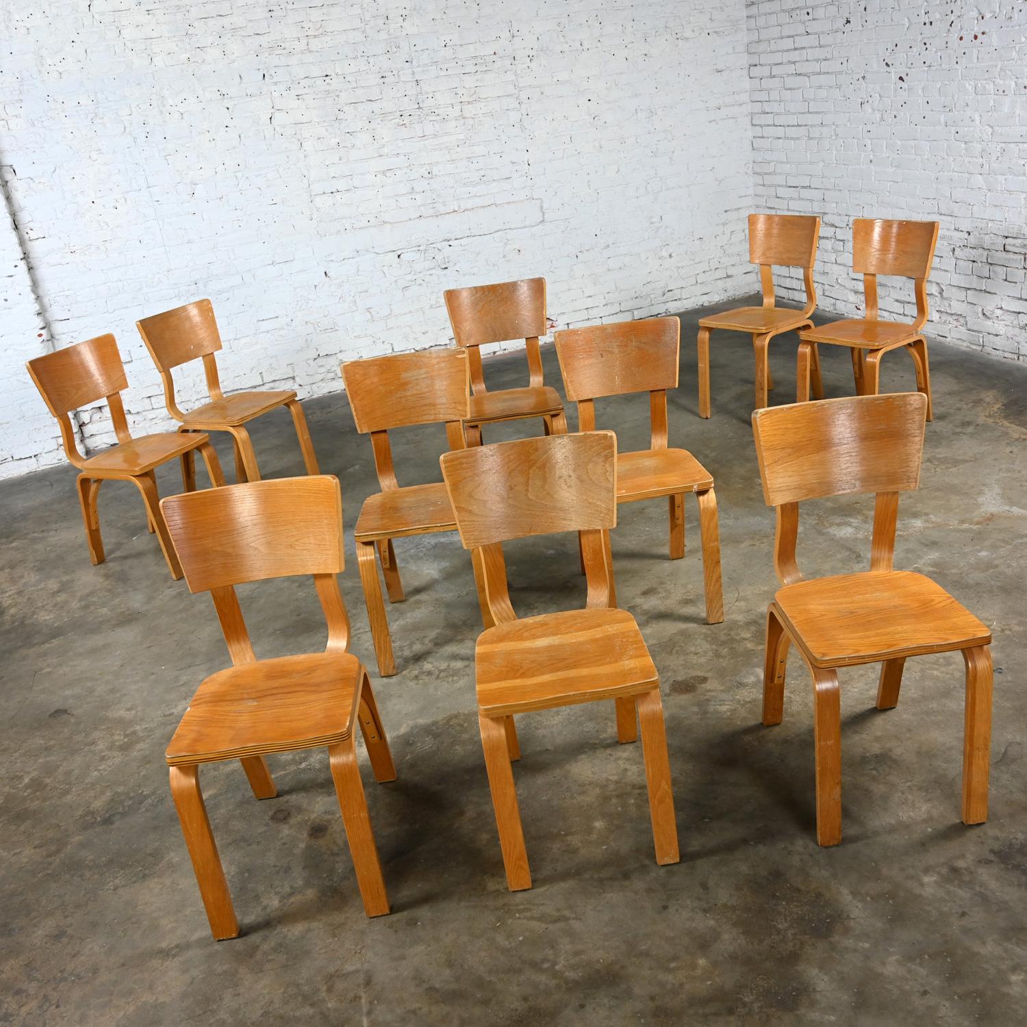 Marvelous vintage Mid-Century Modern Thonet #1216-S17-B1 dining chairs comprised of bent oak plywood with saddle seats and a single bow back stretcher, set of 10. Beautiful condition, keeping in mind that these are vintage and not new so will have
