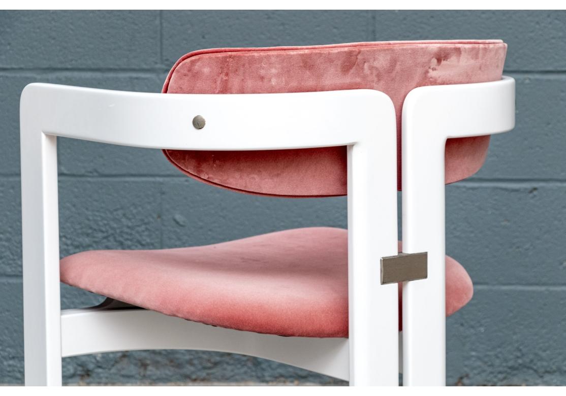 Les chaises, conçues par Augusto Savini dans les années 1960, sont dotées d'un dossier en tonneau en bois laqué blanc. Les pieds avant se fondent doucement dans le dossier en deux parties et se terminent par les pieds arrière. Les cadres sont mis en