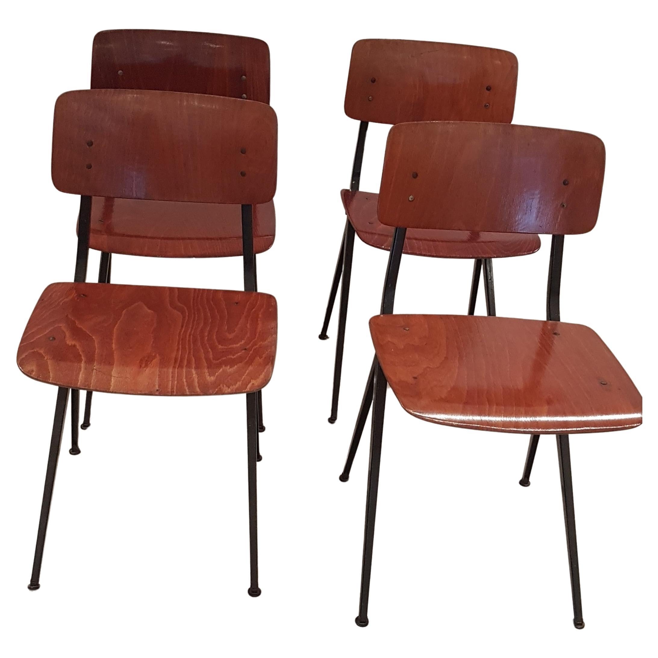 Ensemble de quatre chaises de style industriel par Marko Holland. Ces chaises utilitaires confortables ont de belles assises et dossiers en teck vieilli et des piétements minimalistes en métal laqué noir. Leur simplicité leur permet de s'intégrer