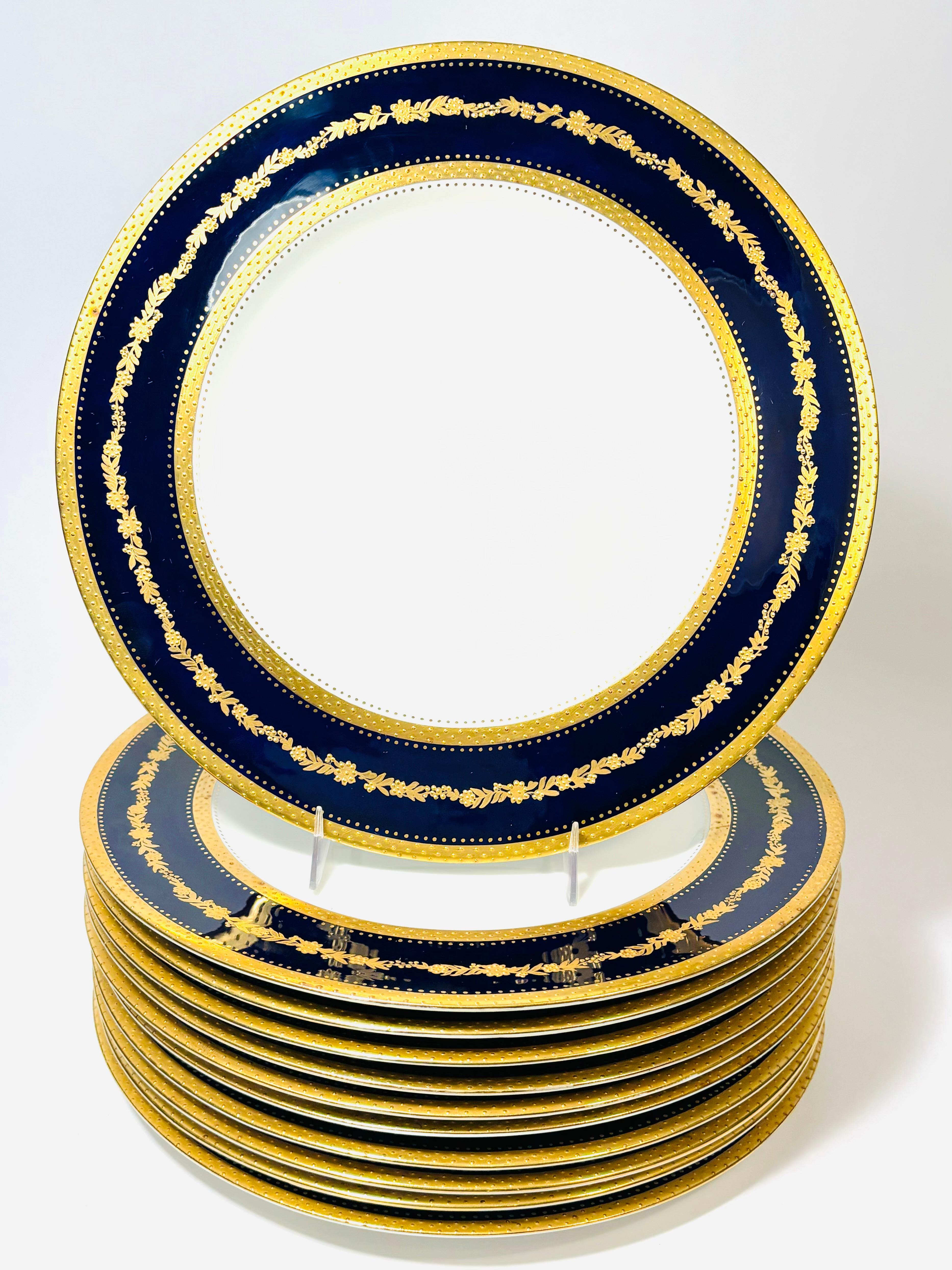 An elegant set of antique dinner plates from the re known firm of George Jones and custom ordered through the New York Gilded Age retailer Higgins & Seiter. A lovely pattern of raised tooled gold is set nicely in its cobalt blue collar. Crisp white
