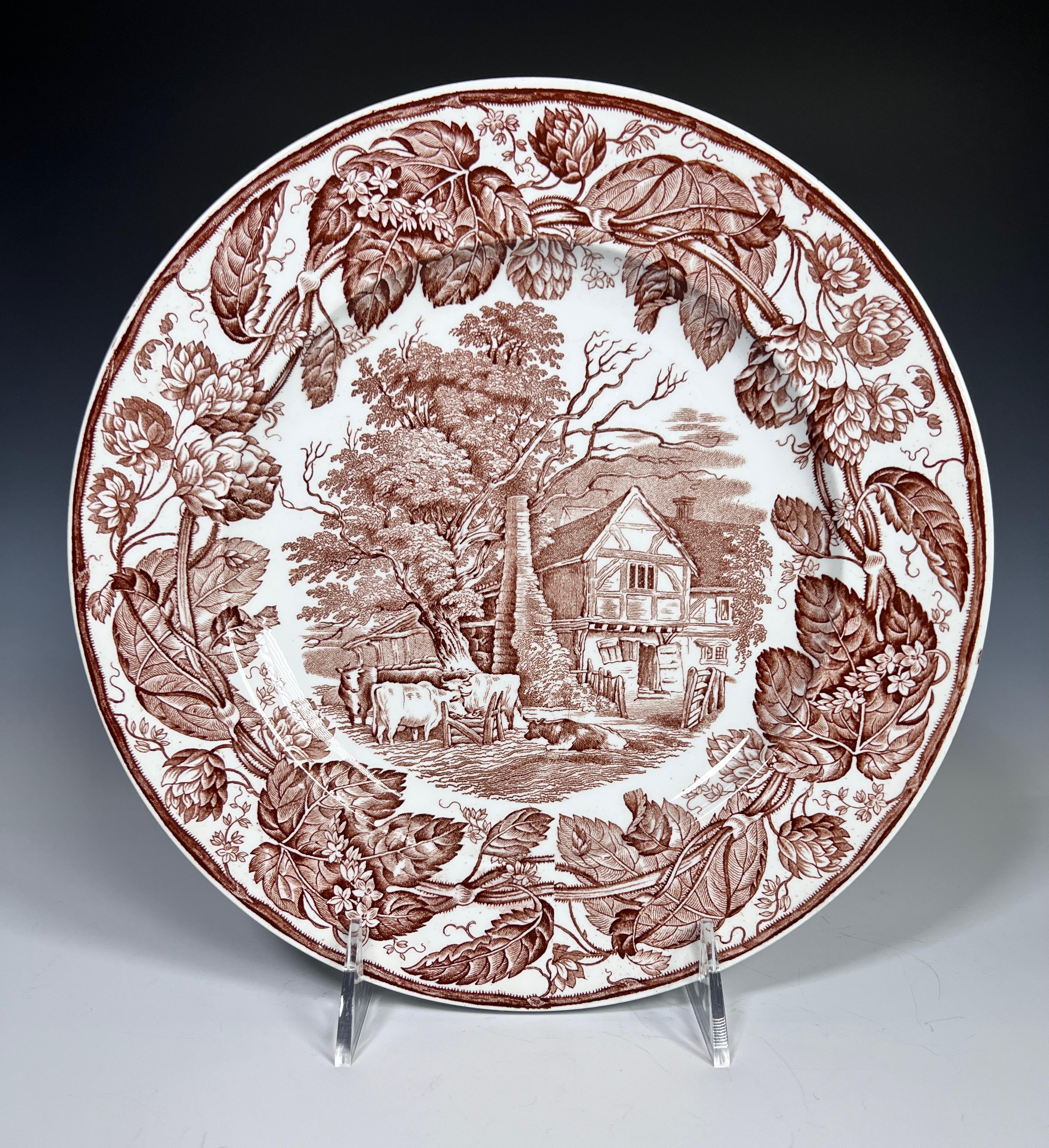A lovely set of 11 dinner plates with a classic countryside subject, depicting a farm scene of cows grazing next to a cottage. The elaborate brown transferware borders feature leaves and flowers encircling the central scene. These are lovely for