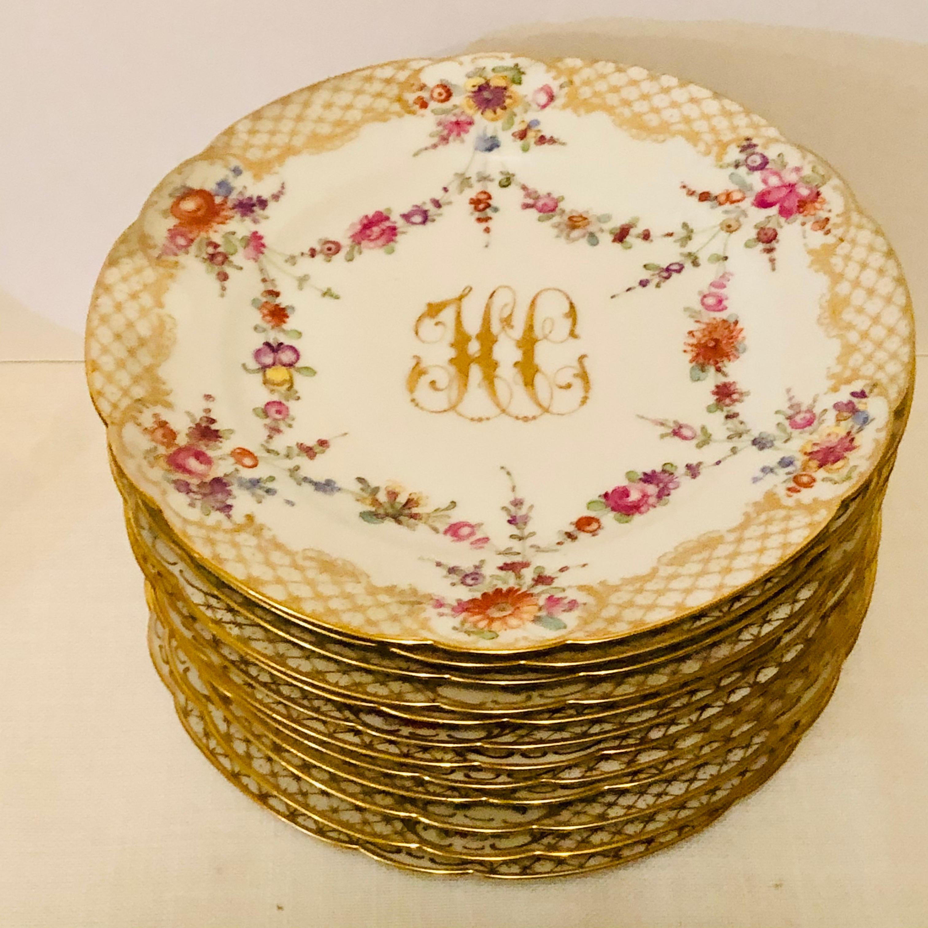 This is a lovely set of twelve Ambrosius Lamm dessert plates. Each plate is painted with different flowers. There is a central raised gold monogram, which is surrounded by a ribbon of flowers. The plates have a border of cross hatched gold and white