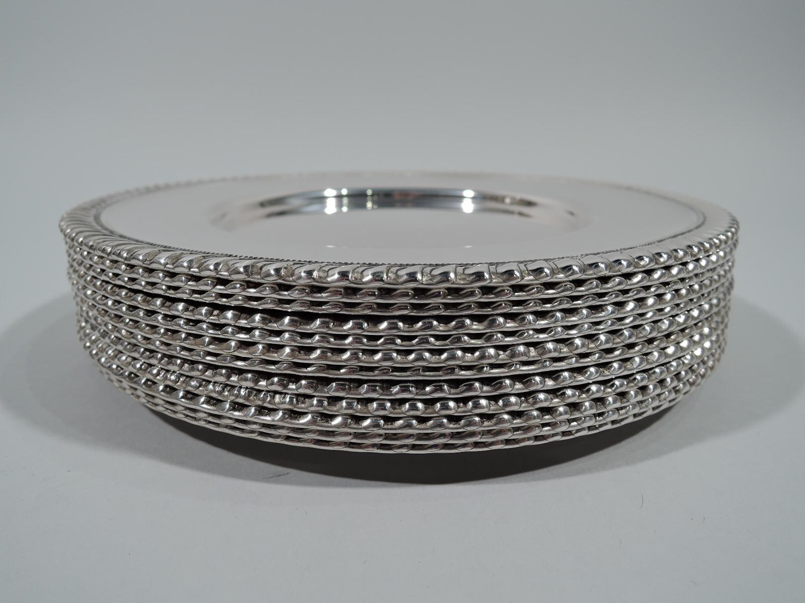 Set of 12 American sterling silver bread and butter plates, circa 1920. Each: Well with tapering shoulder and gadrooned rim. Hallmarked “Sterling”. Heavy total weight: 49.2 troy ounces.