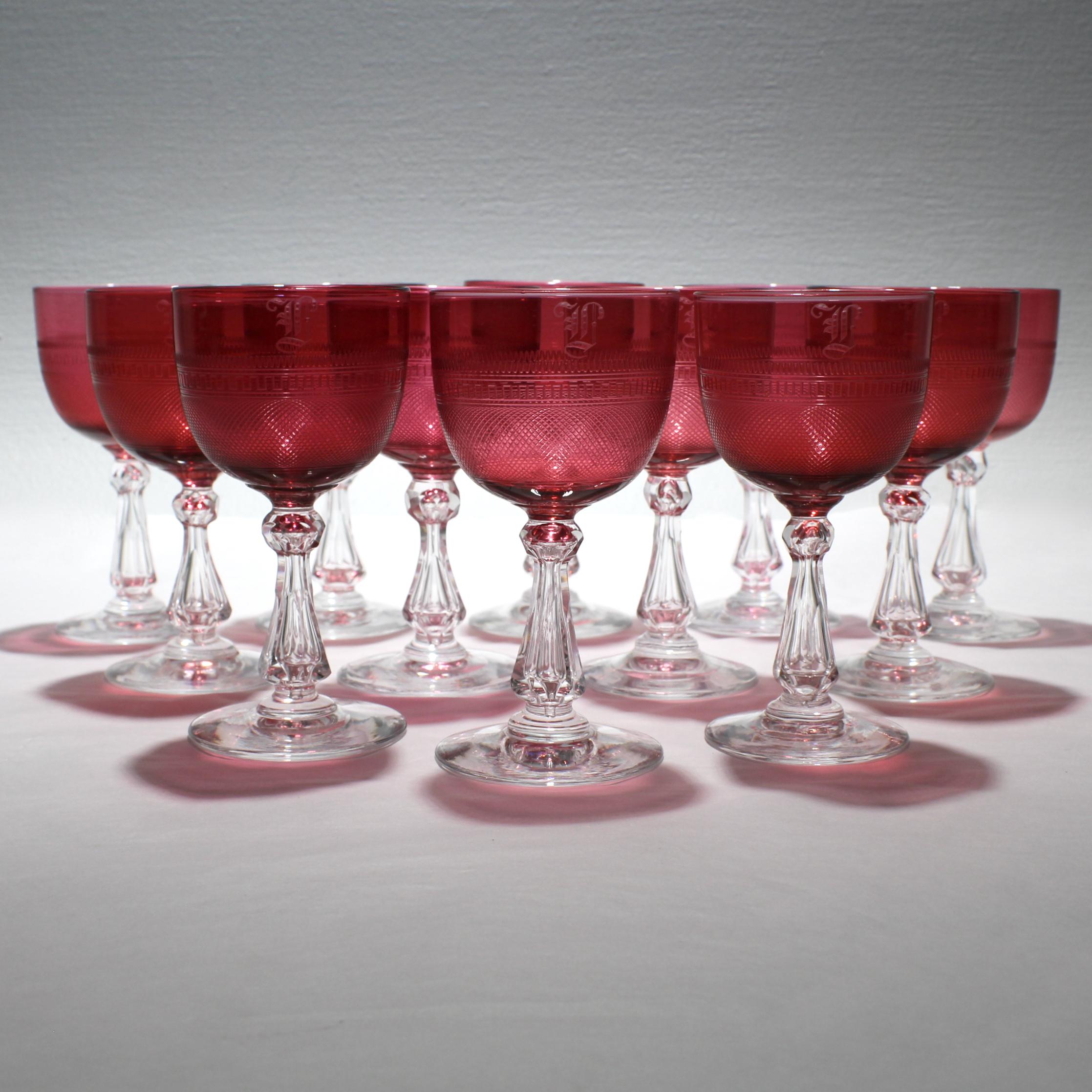 A very fine set of 12 antique English cranberry cordial or sherry wine glasses.

Each has a clear, faceted stem and a red bowl with strawberry field and geometric wheel cut bands. In addition, ten of the stems have an engraved monogram. (Perhaps an