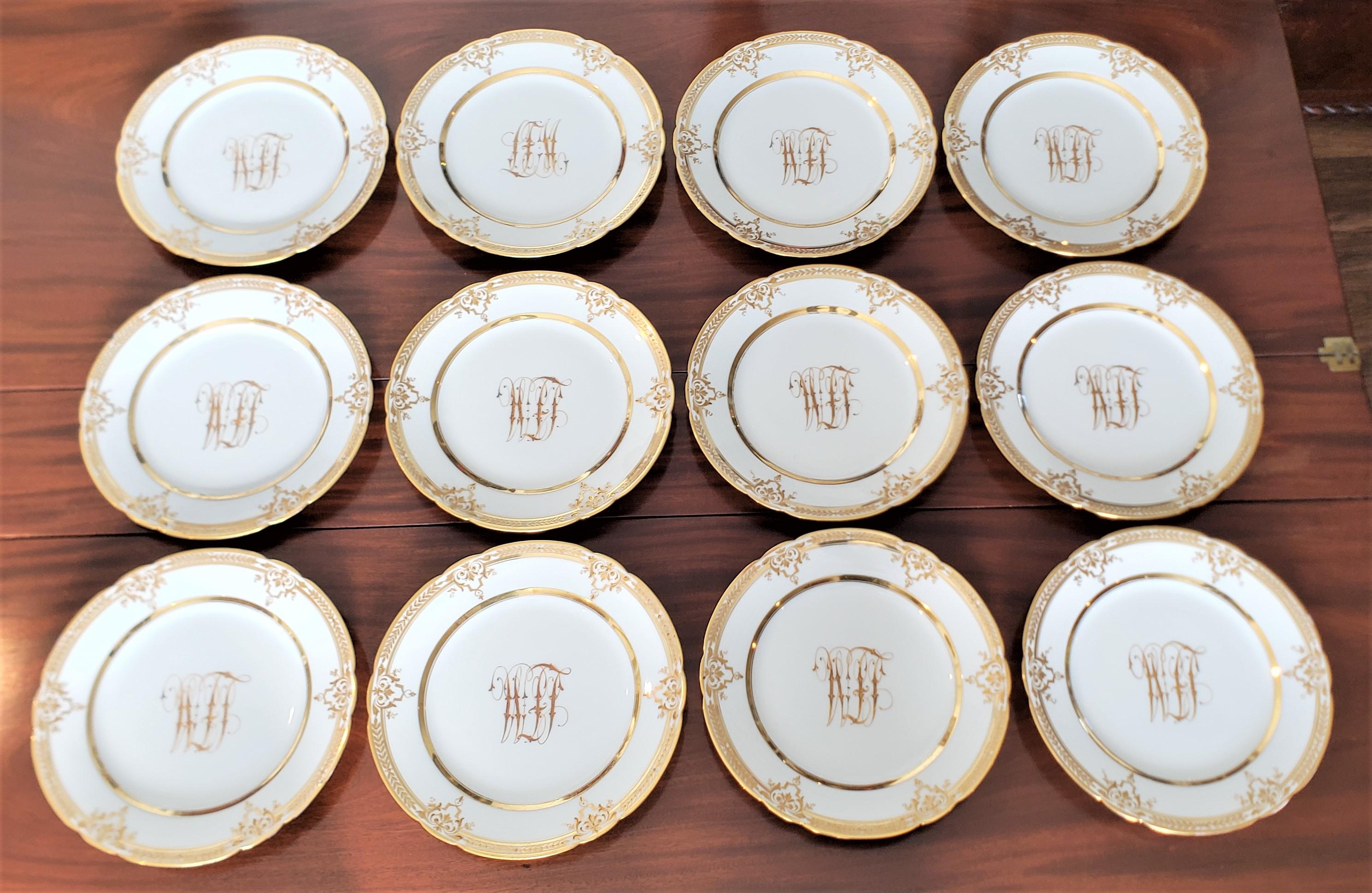 This set of 12 antique porcelain dinner plates were made by the renowned Dresden factory of Germany in approximately 1890 in a Rococo Revival style. The plates are done in white ground with elaborate and ornate gilt hand-painted banding and a large