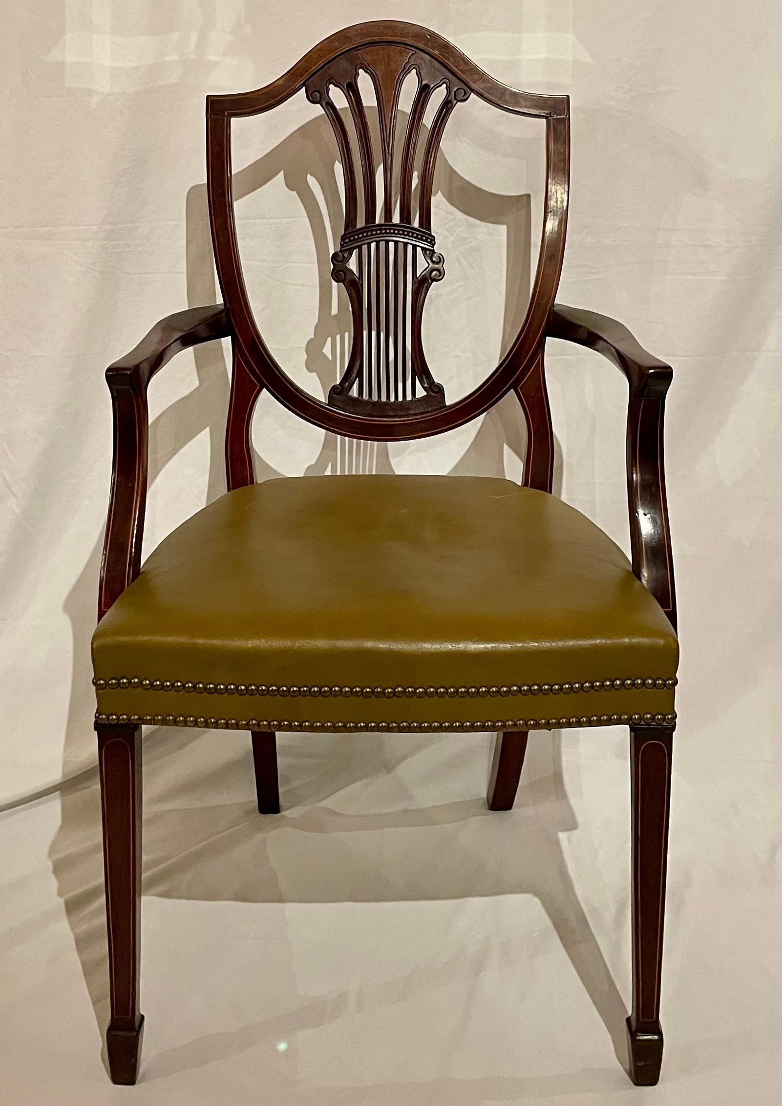 Juego de 12 sillas de comedor inglesas antiguas de caoba estilo Sheraton con asientos de cuero, circa 1920-1930.  Adquirida en un domicilio particular.
Sillones: 2
Sillas auxiliares: 10