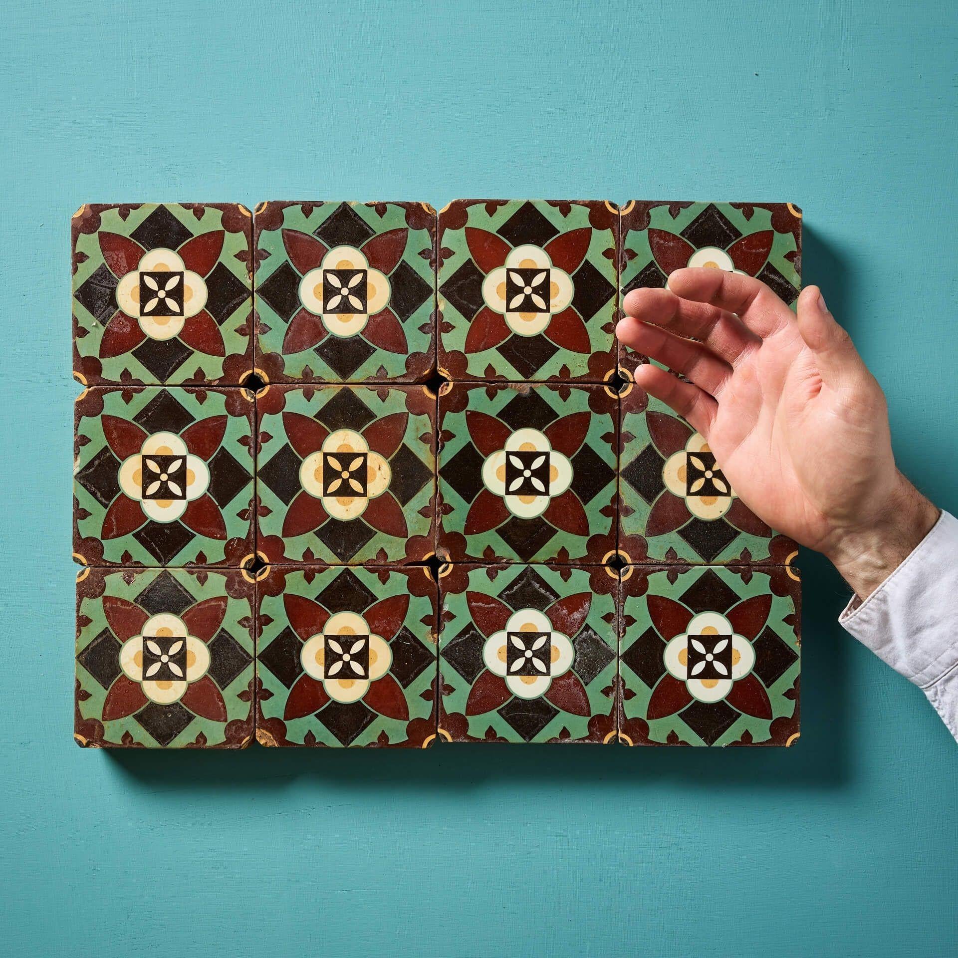 Twelve 4-inch antique encaustic tiles by Minton & Co, beautifully glazed with floral embellishments on a green, black and red backdrop.

Dating back to circa 1870, these reclaimed tiles have stood the test of time, with age related wear that only