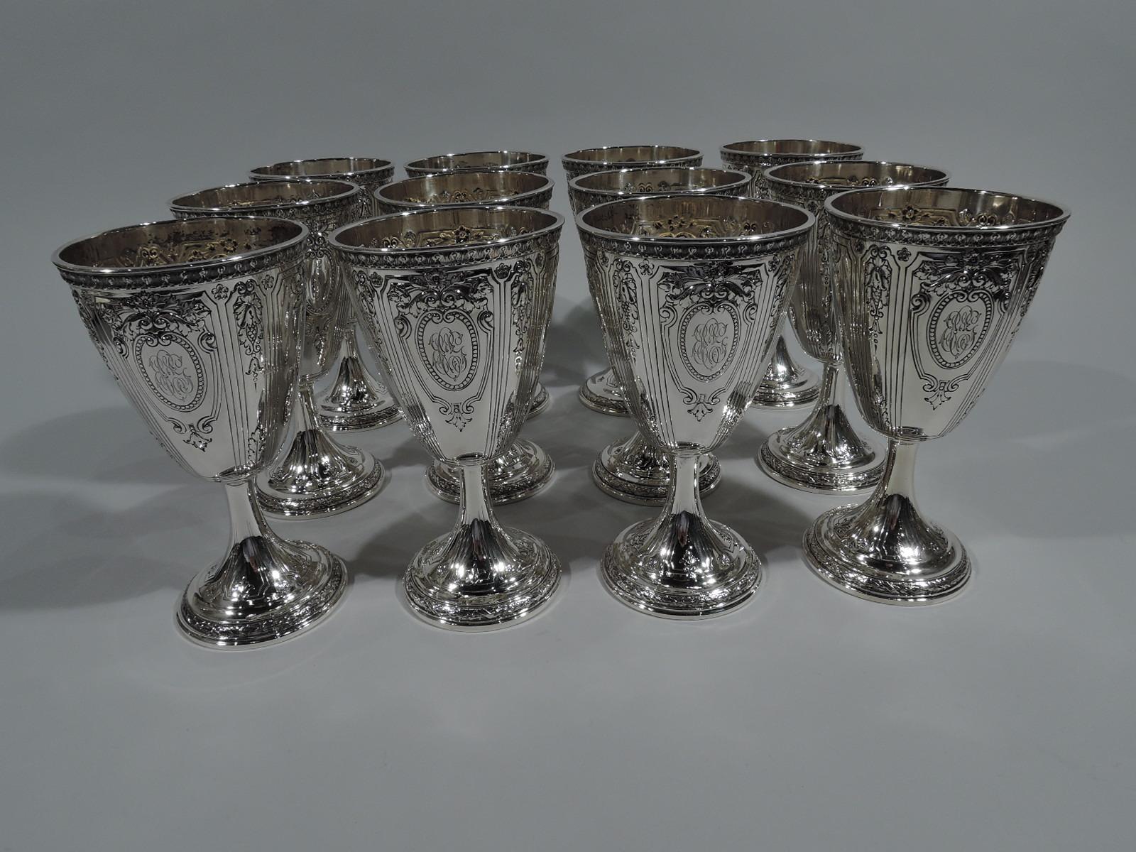 Set of 12 sterling silver goblets in Maintenon pattern. Made by Gorham in Providence in 1929. Each: conical bowl on cylindrical stem terminating in raised foot. Curvilinear frames inset with foliage and flowers, as well as 2 2 beaded scroll