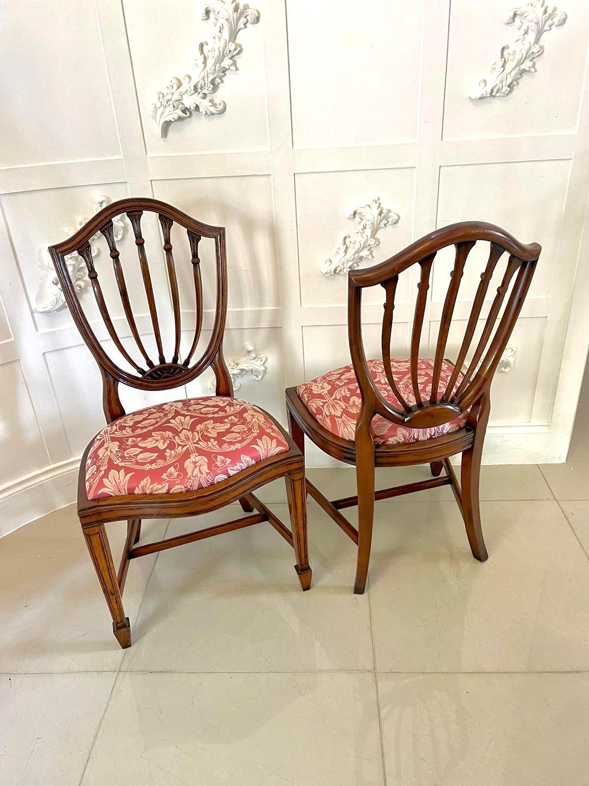 Set of 12 antique quality mahogany shield shaped back dining chairs consisting of two elbow and ten single chairs having a quality mahogany shield shaped backs with five carved mahogany splats to the centre, newly reupholstered drop in serpentine