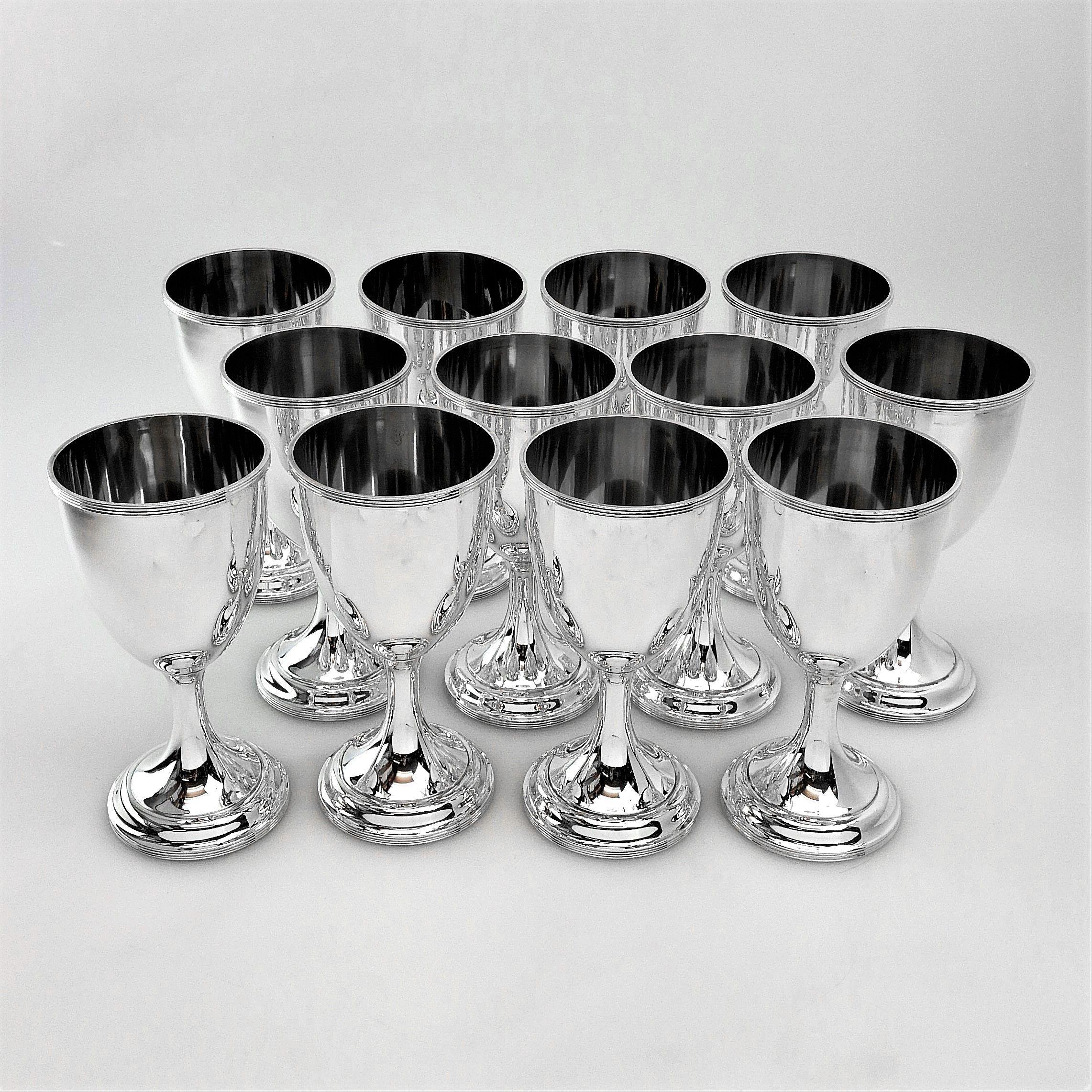 A set of 12 antique solid Silver Wine Goblets / Drinking Goblets standing on a wide spread pedestal foot. The Goblets are simple and elegant in plain highly polished silver with an understated band of reeding on the lip and foot. 
 
Made in America