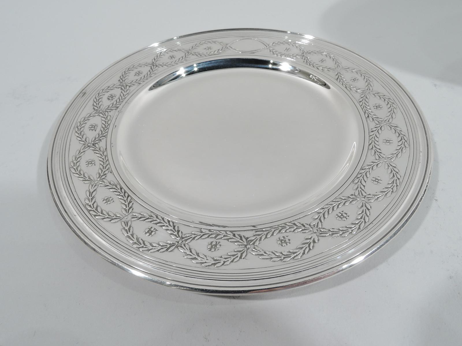 Set of 12 Winthrop sterling silver bread and butter plates. Made by Tiffany & Co. in New York, ca 1920. Each: Round well and wide shoulder with acid-etched laurel-wreath border inset with flower heads. Fine pieces in the historic pattern that was