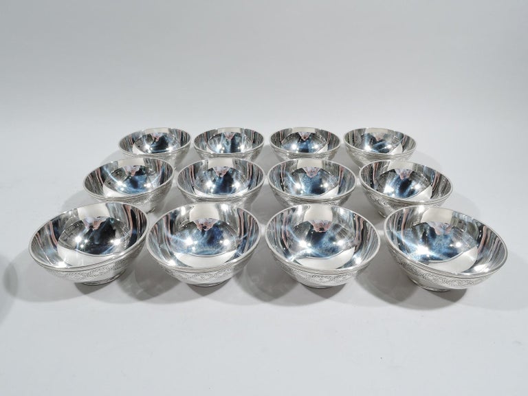 Set of 12 Winthrop sterling silver bowls. Made by Tiffany & Co. in New York, ca 1920. Each: Curved sides with acid-etched laurel-wreath border inset with flower heads, and short, reeded, and inset foot. Fine pieces in historic pattern that was first