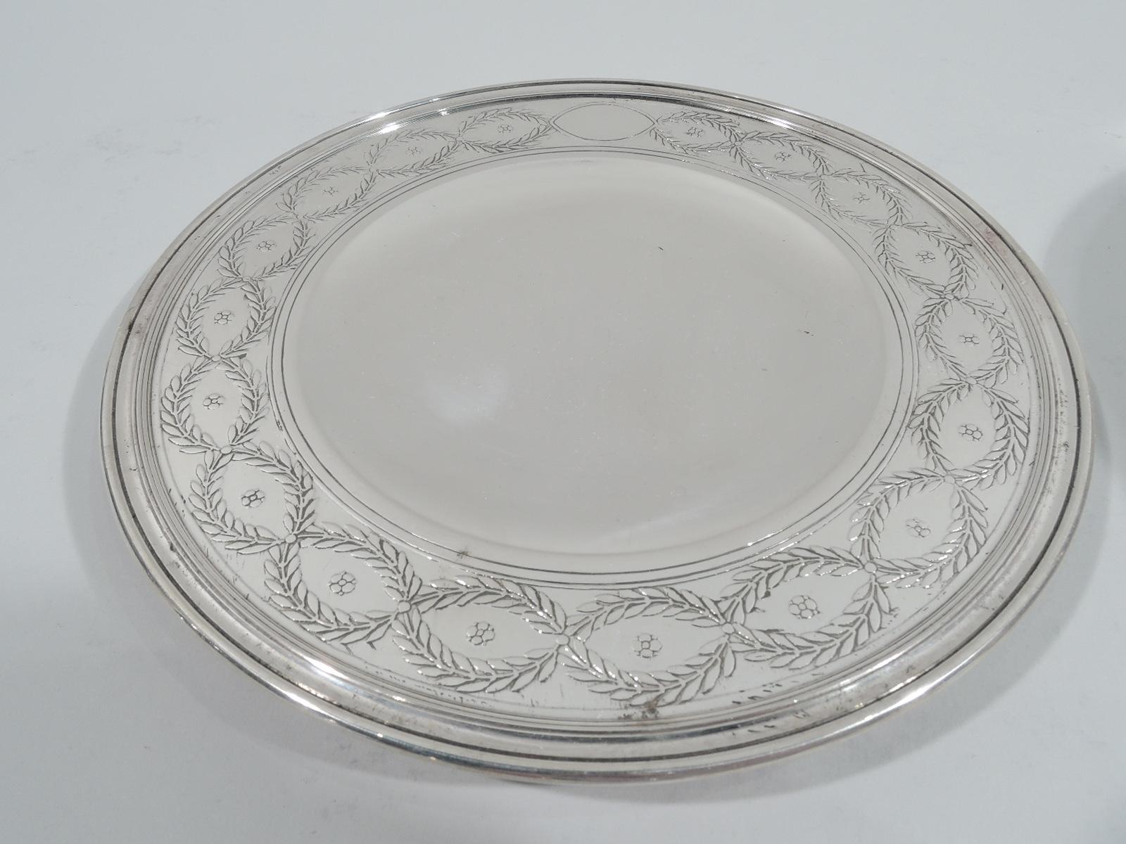 Set of 12 Winthrop sterling silver dessert plates Made by Tiffany & Co. in New York, ca 1920. Each: Round and curved well and wide shoulder with acid-etched laurel-wreath border inset with flower heads, and short inset foot. Fine pieces in the
