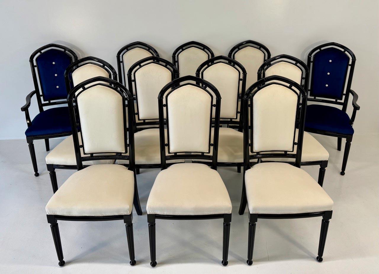 Ensemble raffiné de 12 chaises de style Art Déco, dont 10 chaises tapissées de velours ivoire et 2 chaises trônes en velours bleu, parfaites comme sièges de tête.
La finition laquée noire renforce le contraste chromatique, créant un effet
