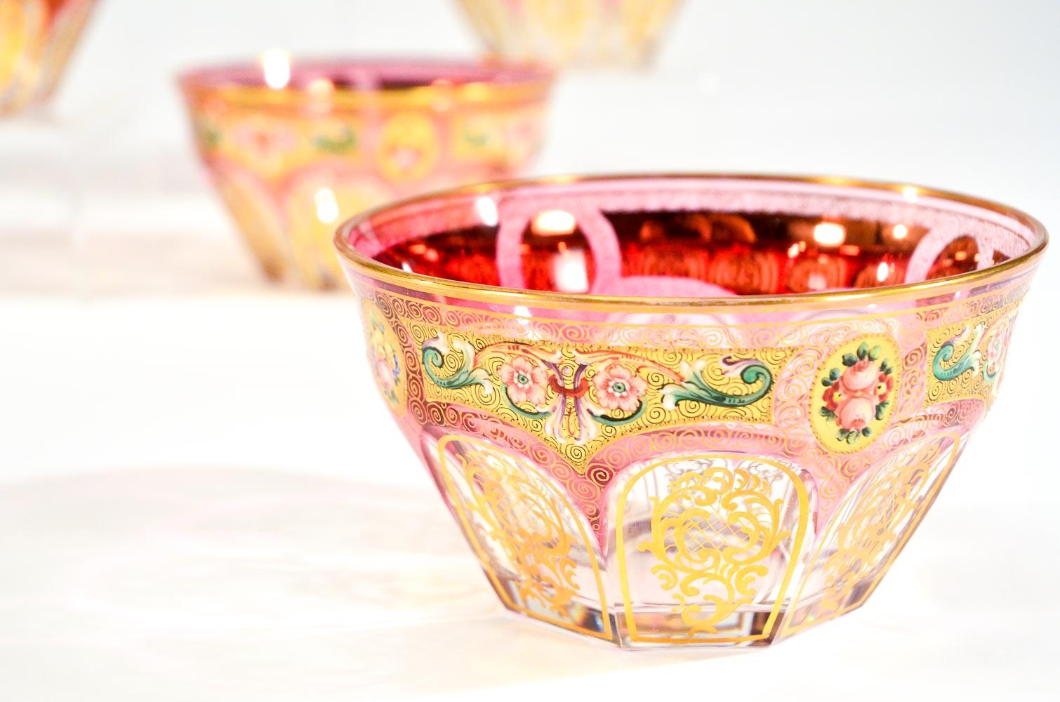 This is an exquisite set of 12 handblown cranberry overlay cut to clear crystal bowls which are finely hand painted with polychrome enamel and gold decoration. The bowls were made by Baccarat and decorated in the Moser factory by their master