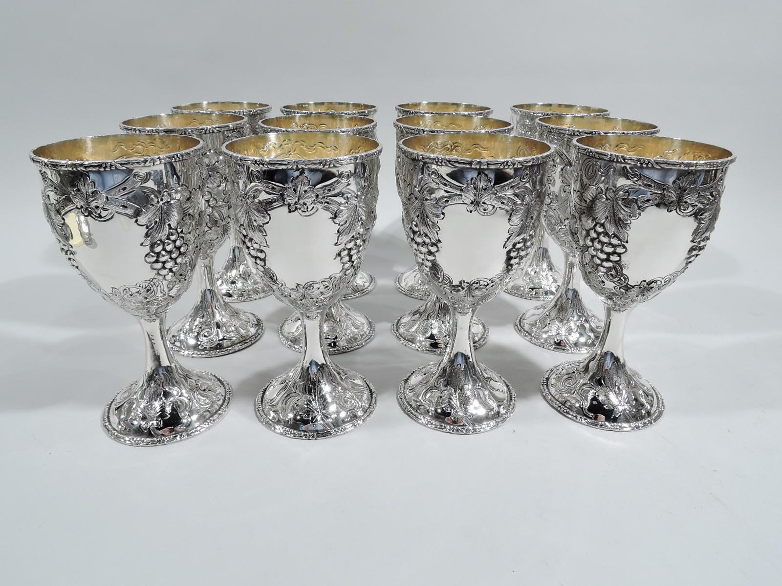 Set of 12 turn-of-the-century sterling silver wine goblets. Made by AG Schultz & Co. in Baltimore. Oval bowl on upward tapering stem flowing into raised foot. Chased and engraved fruiting grapevine wraps around bowl with oval frame (vacant) between