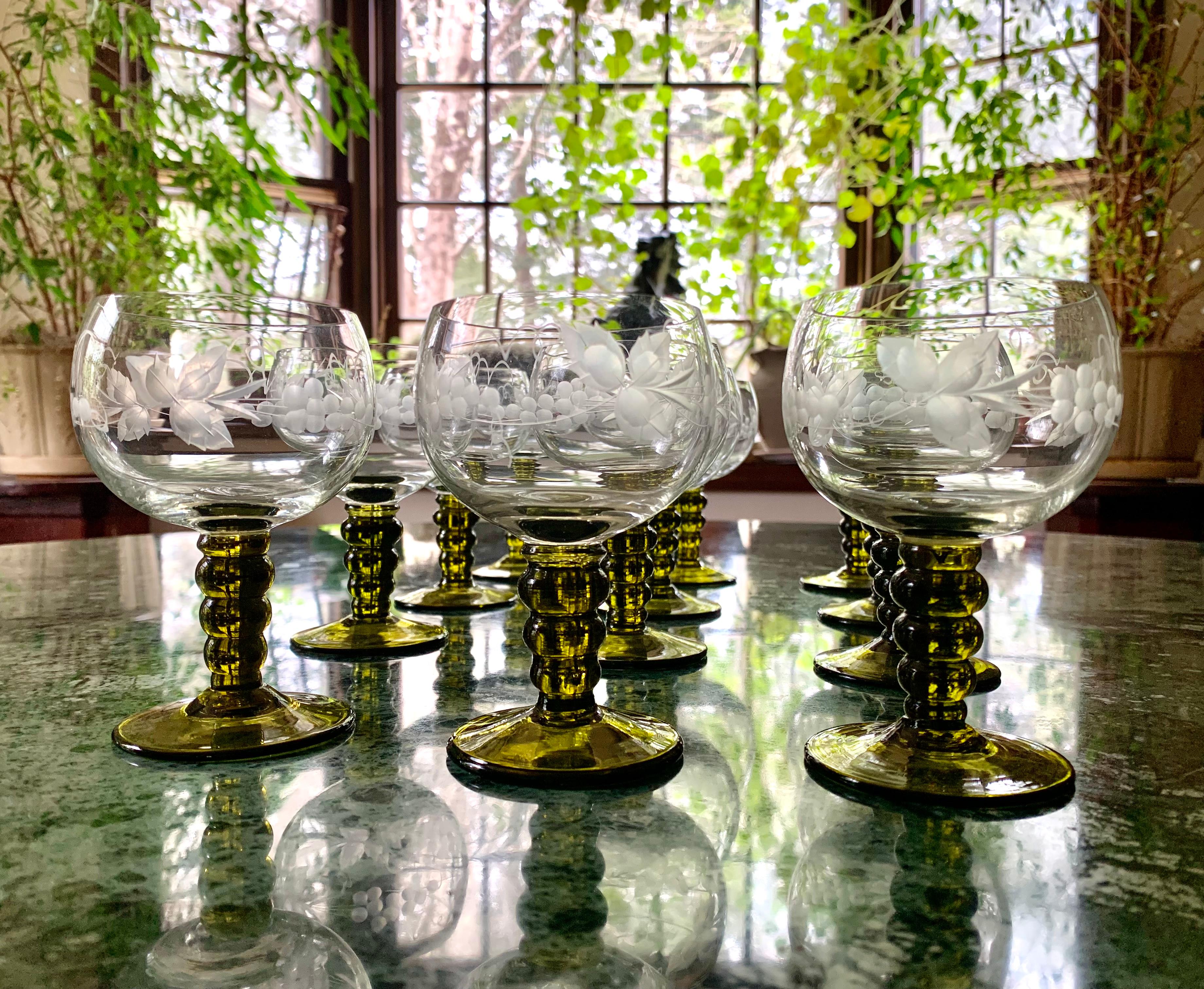 Wonderful for garden parties, this set of twelve Bohemian Rhine wine glasses features an engraved grapevine motif on the body of the glass and green stem. Several glasses have an engraved fleur-de-lis mark on the bases.
All pieces in excellent