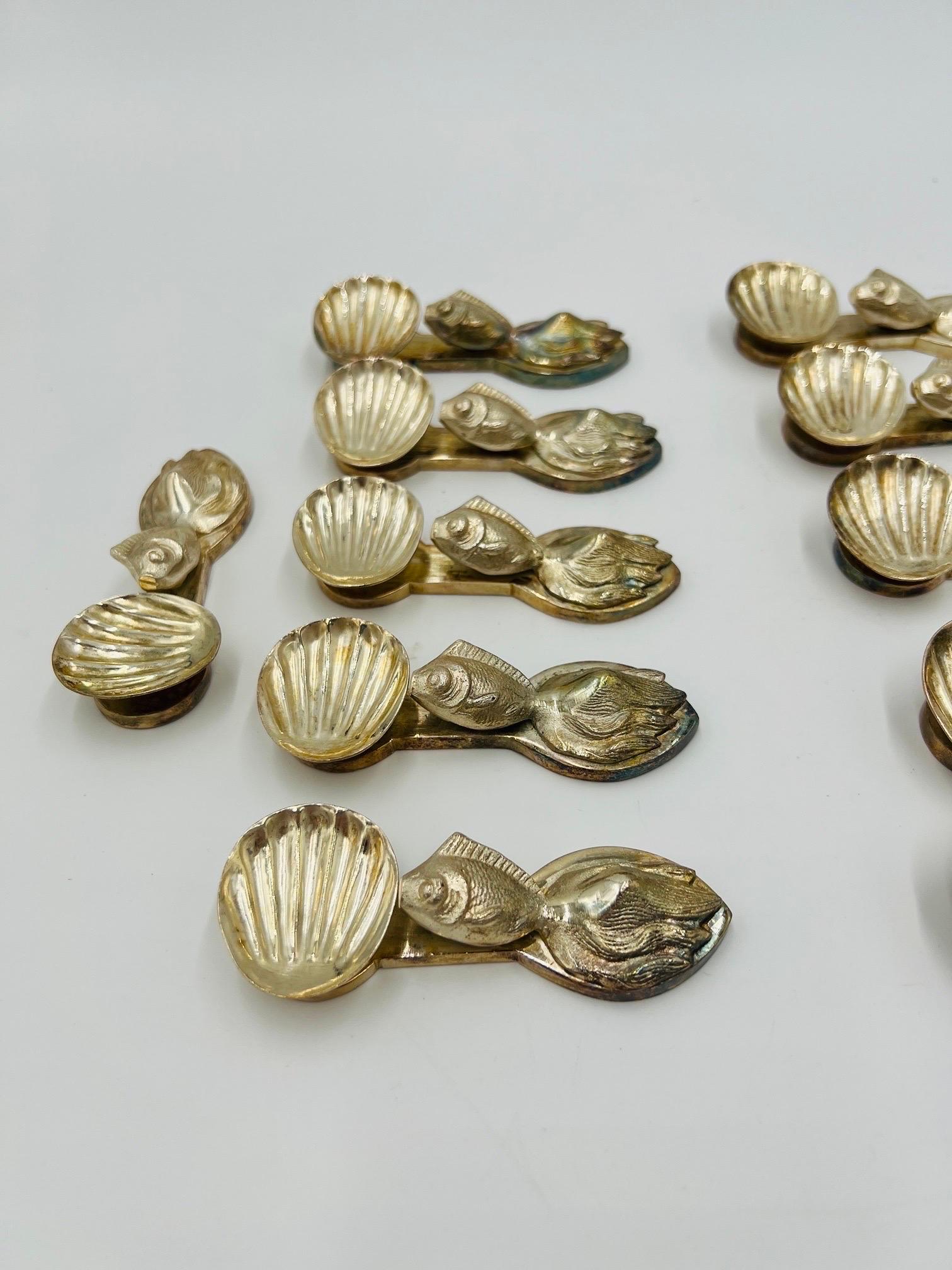 A set of 12 unique individual salt cellars. Each reminiscent of the famous Buccellati silver factory in Italy. They each have a goldfish laying flat across the body and a half shell cellar on the other. Heavy silver-plate over bronze or heavy metal.