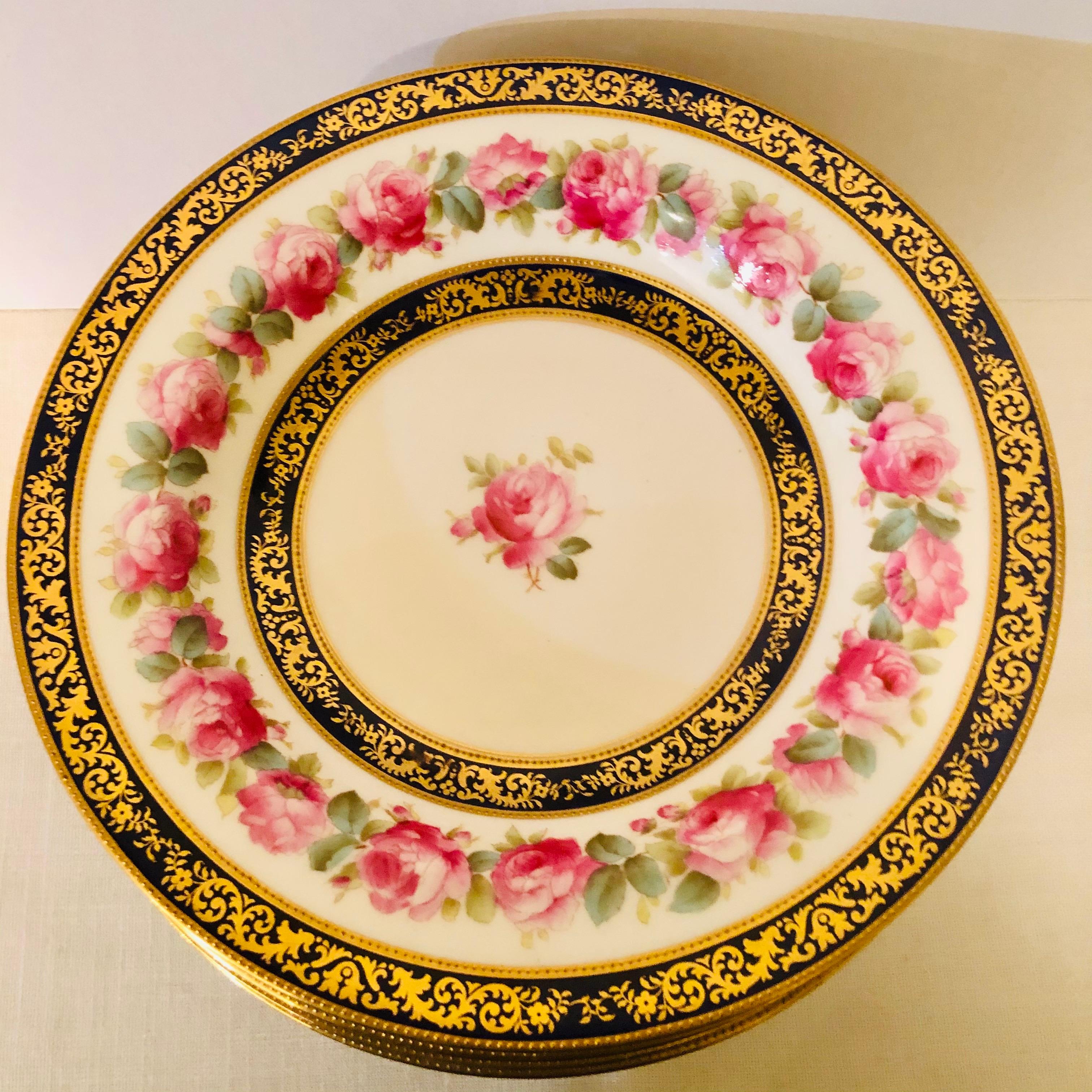 This is a stunning set of twelve Cauldon English wide rim soup bowls. They are decorated with a central pink rose with a ring of beautiful pink roses on their inner border. The central rose and the ring of roses are each surrounded by a cobalt