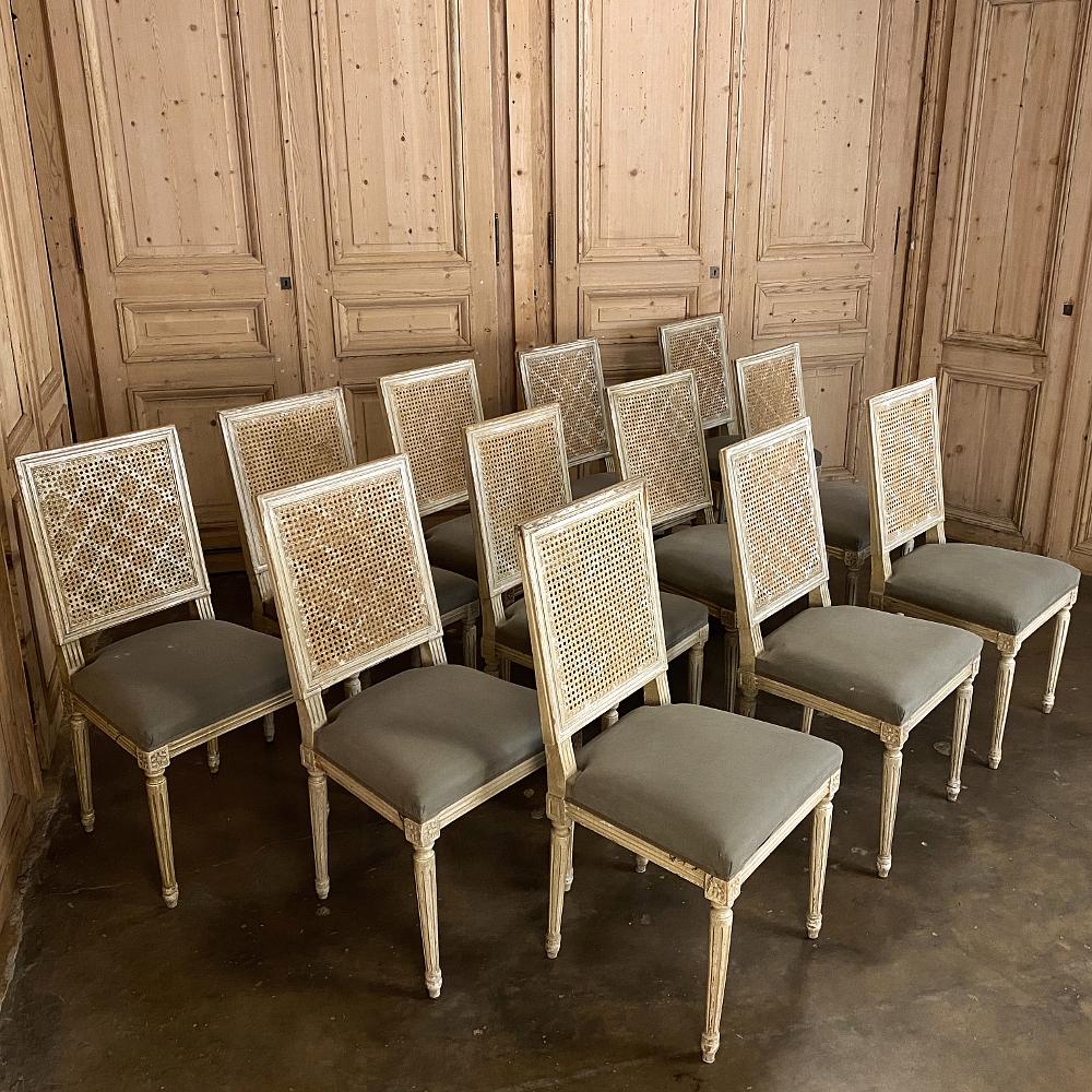 Set of 12 antique French Louis XVI dining chairs feature upholstered seats, tailored architecture, and caned seatbacks that not only provide comfort but light weight as well! What a great find in a set of twelve, especially with a painted patinaed
