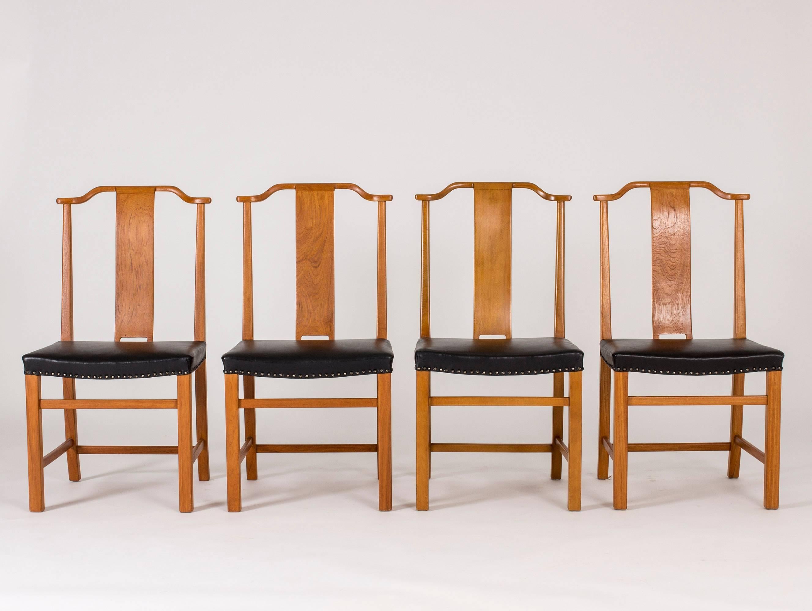 Set of 12 beautiful dining chairs in stained elmwood and leather by Axel Larsson, custom made for a Swedish Court of Appeals. Dignified design with tall backs, discreet curves and a stabile base.