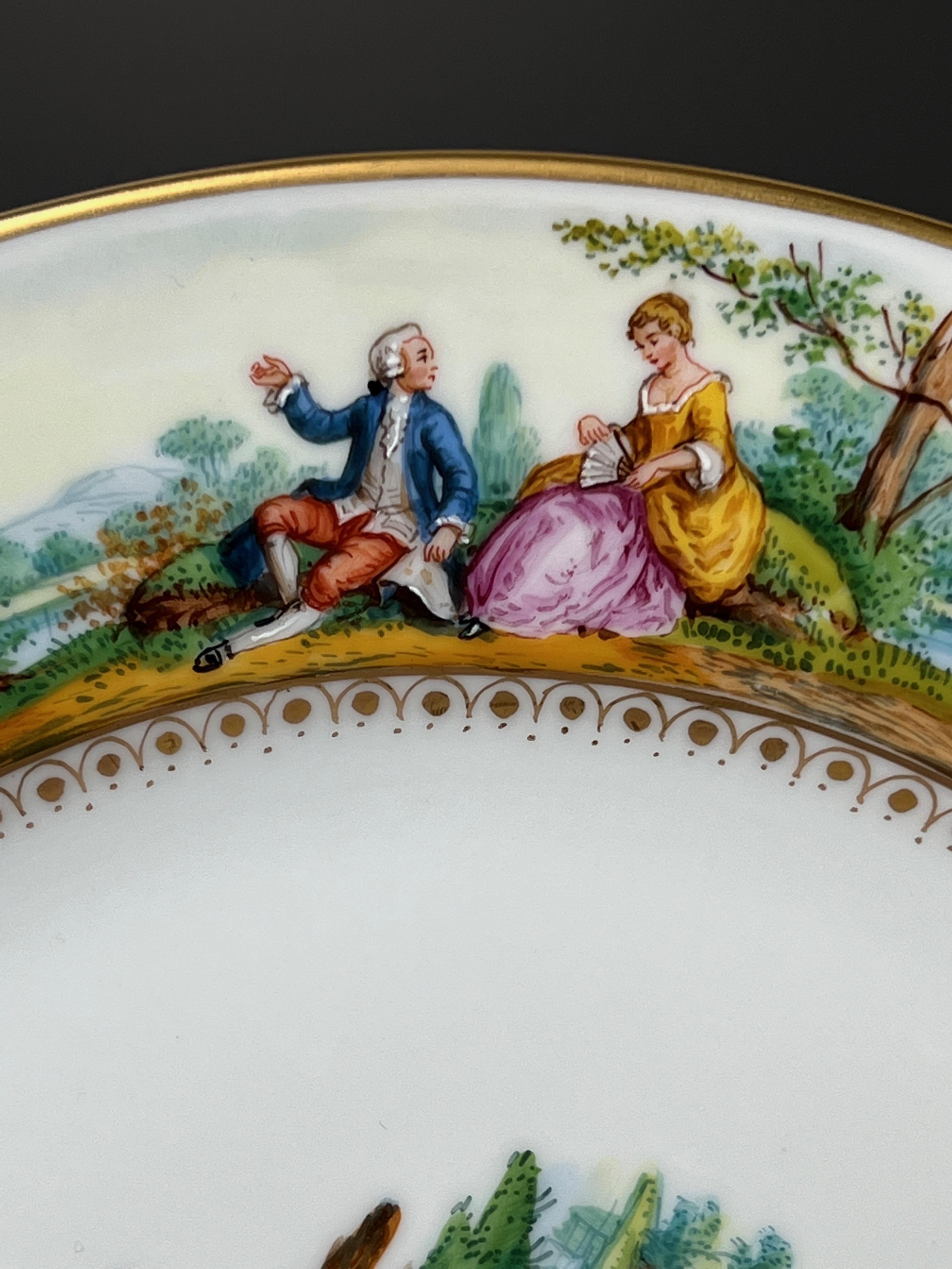 Il s'agit d'un ensemble de 12 assiettes à dîner Dresde peintes à la main, représentant des scènes classiques de Watteau entourant les bordures avec des centres peints à la main de façon magistrale, chaque scène étant unique. Les sujets centraux sont
