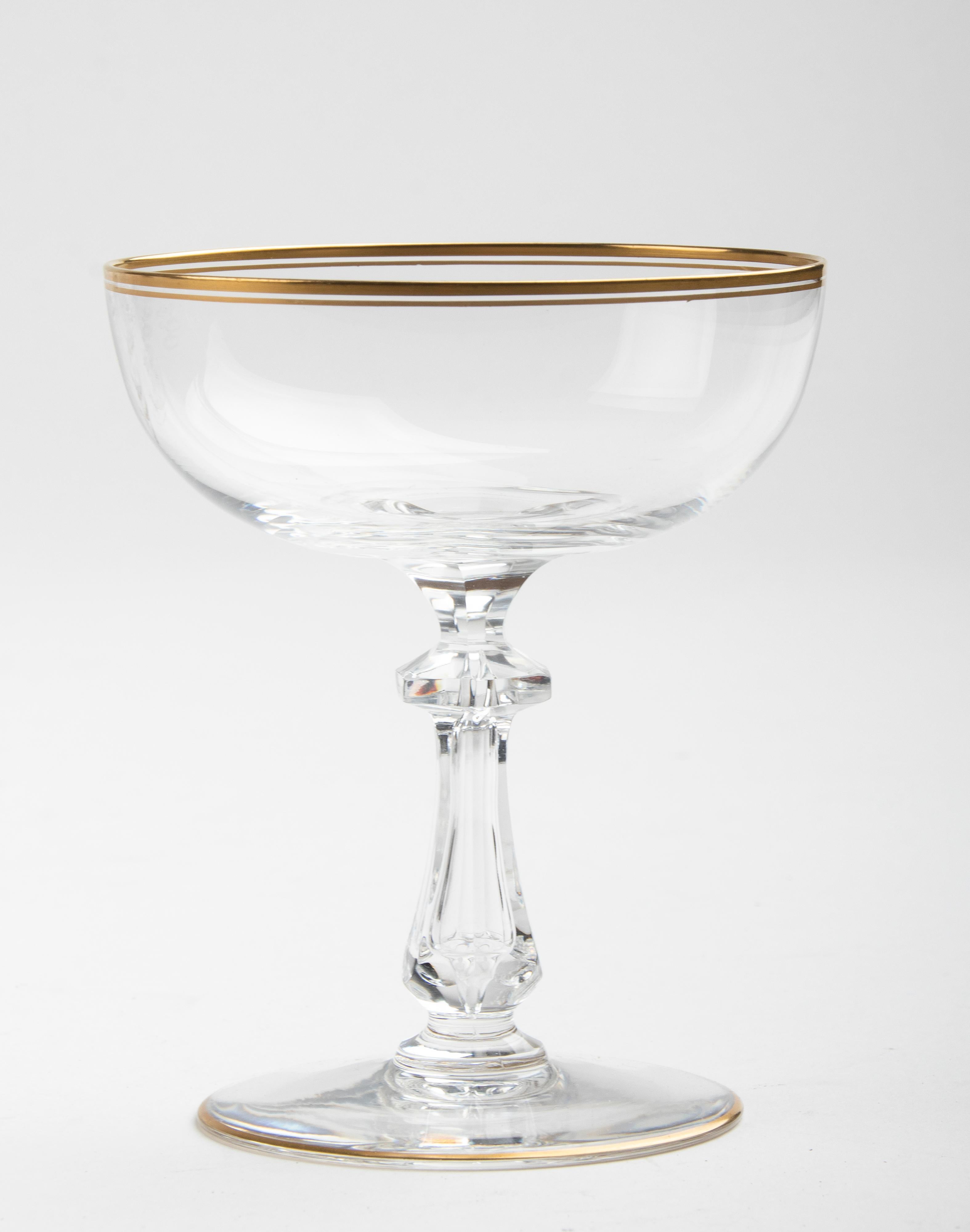 Beautiful set of 12 crystal champagne coupes or cocktail glasses. The crystal is of a very refined quality. The stem and foot are strong, the calyxes are thin. The glasses are decorated with narrow gold-coloured edges and the inside of the stem is