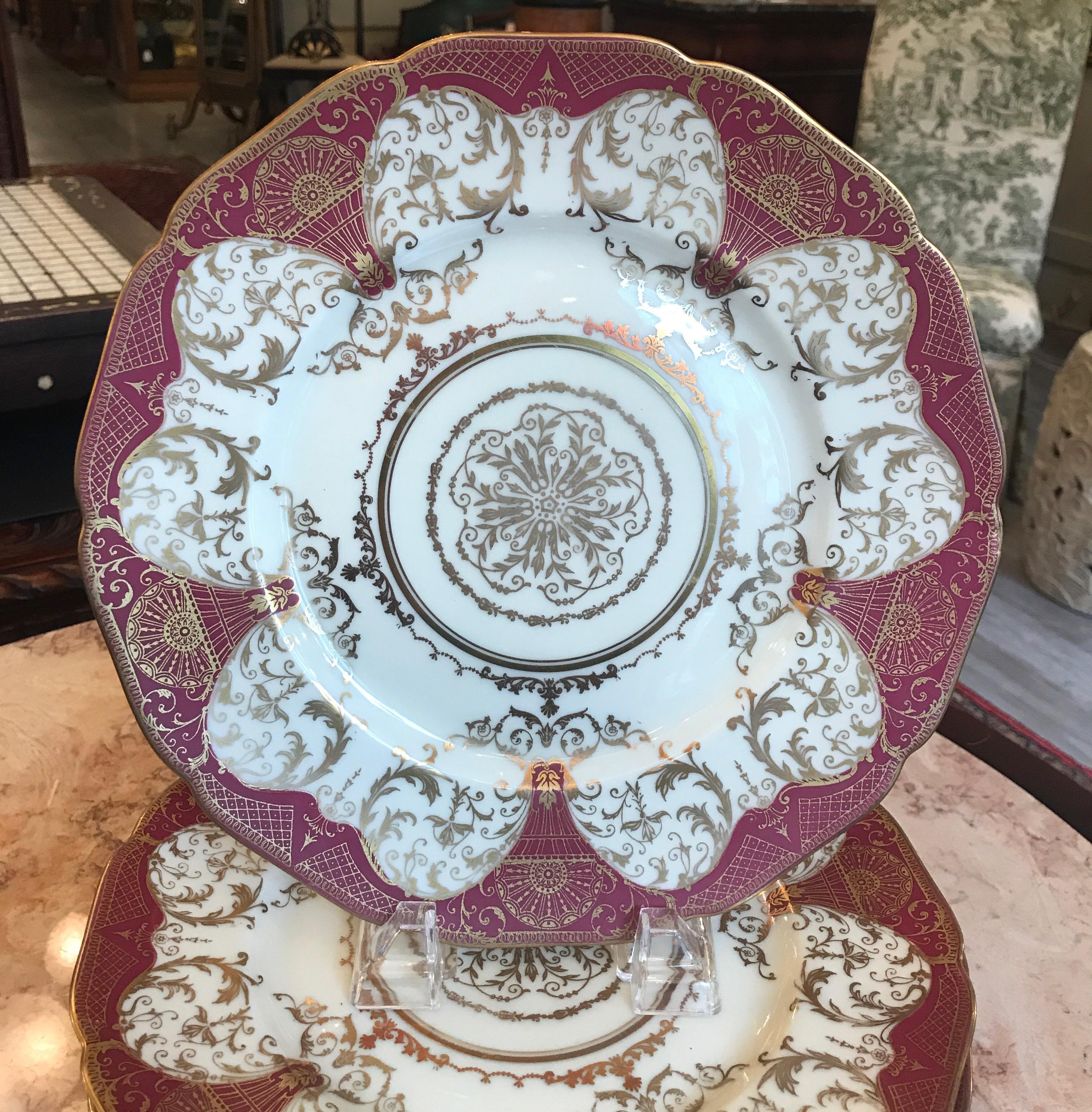 An elegant set of 12 gilt decorated service dinner plates by Black Knight, early 20th century. Unusual red clay color background with elaborate gilt overlay detail with centre medallion. Centre lacy medallion with circular gold bands around. Price