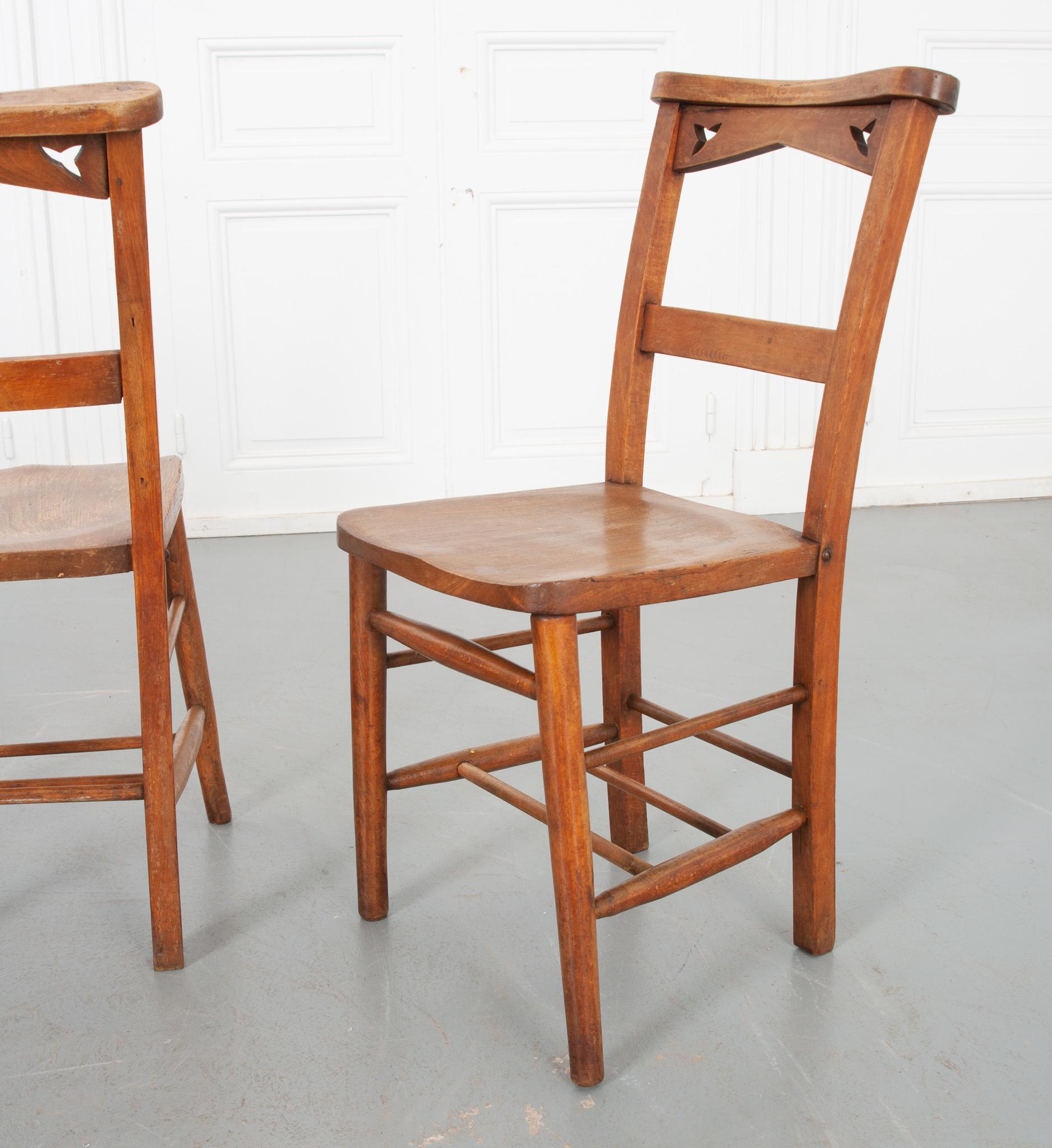 These unique chairs are sold as a set of twelve, eight of which have book holders attached to the back, as they were once used in a church setting. The top of the chairs have a slight downward slope, possibly shaped for those in the row behind to
