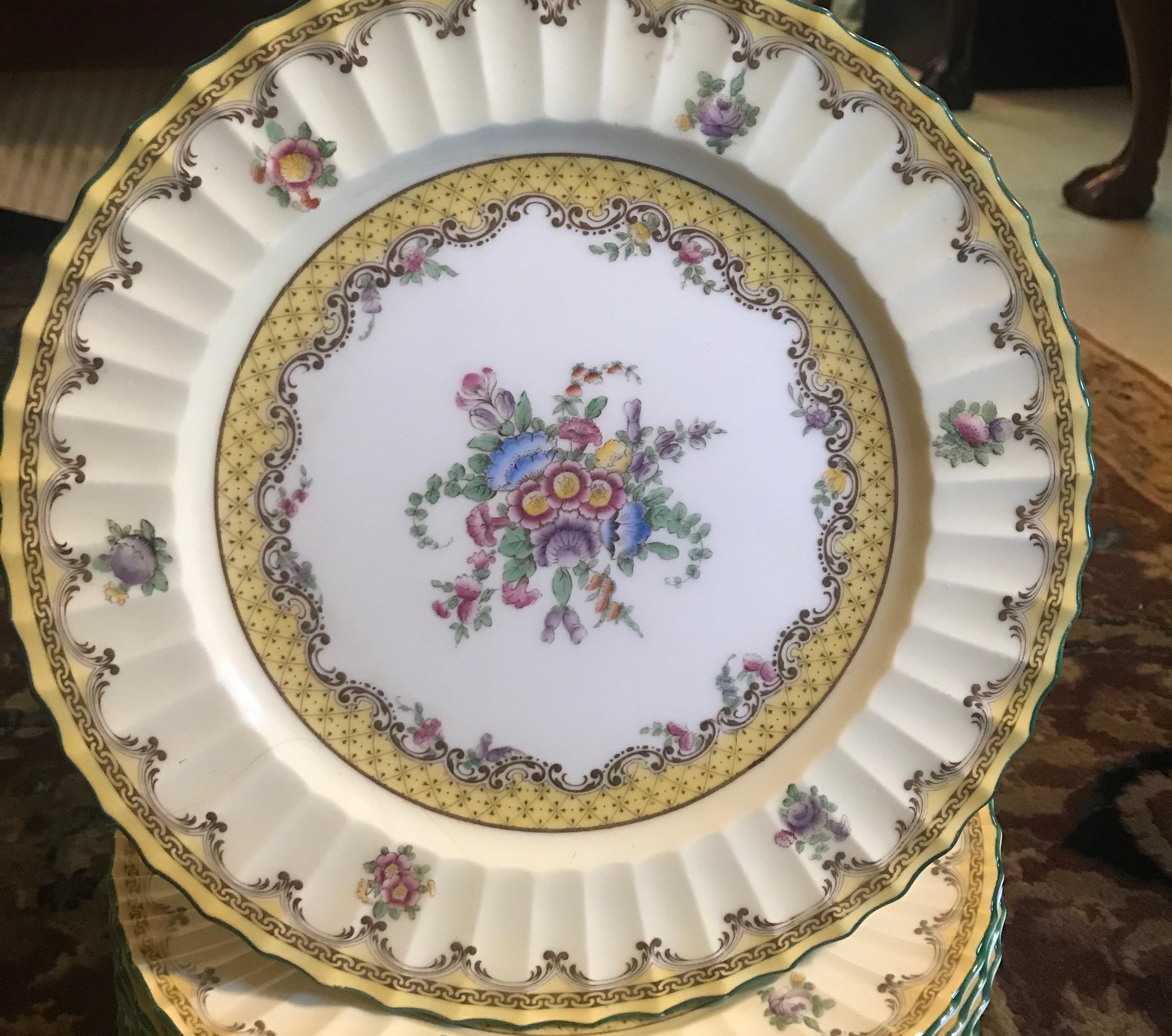 A set of 12 English Royal Worcester floral service plates titled Willoughby. The set was made in the early 1930s and was resurrected from Royal Worcesters pattern from 1770. The same painted decoration and color palette was used on these plates as