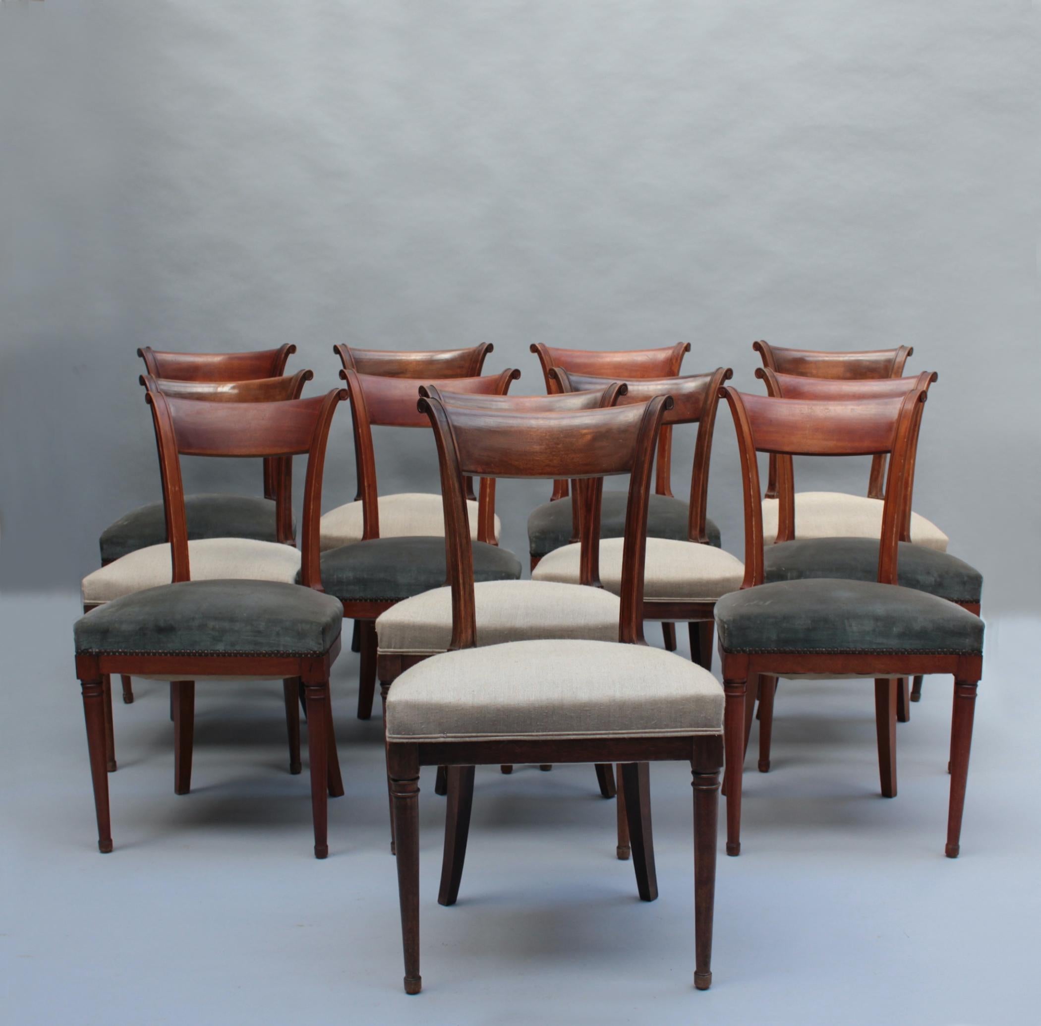 A set of twelve fine French Art Deco mahogany side chairs with a curved back, fluted back post, and turned wood details on front legs.