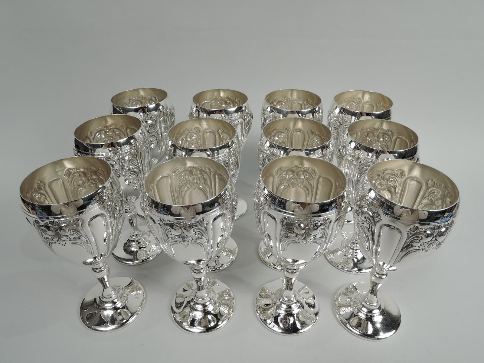 Set of 12 Victoria sterling silver goblets. Made by Fisher Silversmiths, Inc. in Jersey City, New Jersey. Each: Ovoid bowl on baluster stem on raised foot. Bowl has leafing scrolled frames (vacant) between lobes. Pretty with old fashioned charm.