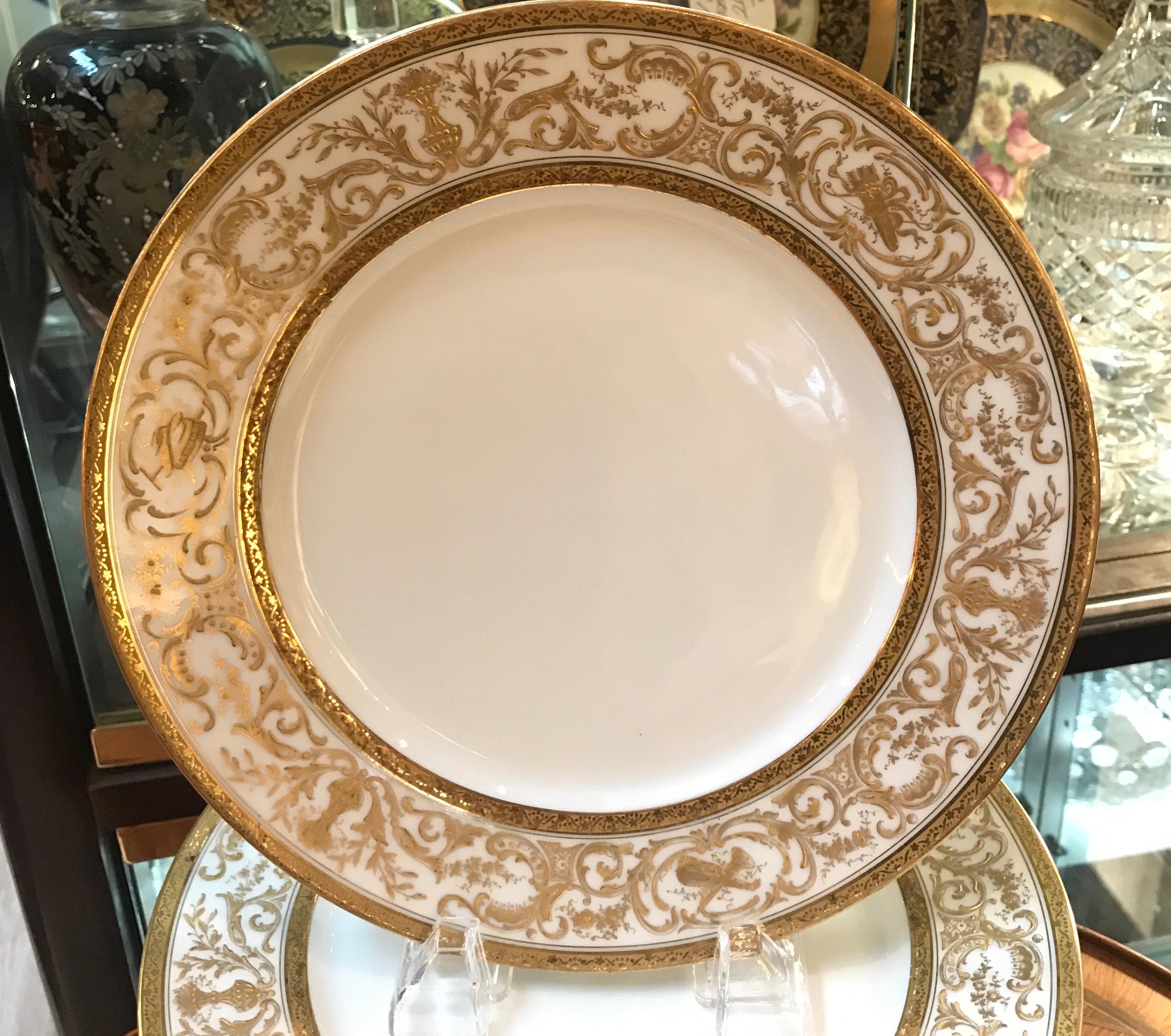 A set of elegant French porcelain raised gilt 9.75 inch dinner plates. The smaller dinner plates are the classic size from circa 1900 with a white porcelain body with delicate and lacey hand applied raised gilt decoration. The plates were retailed