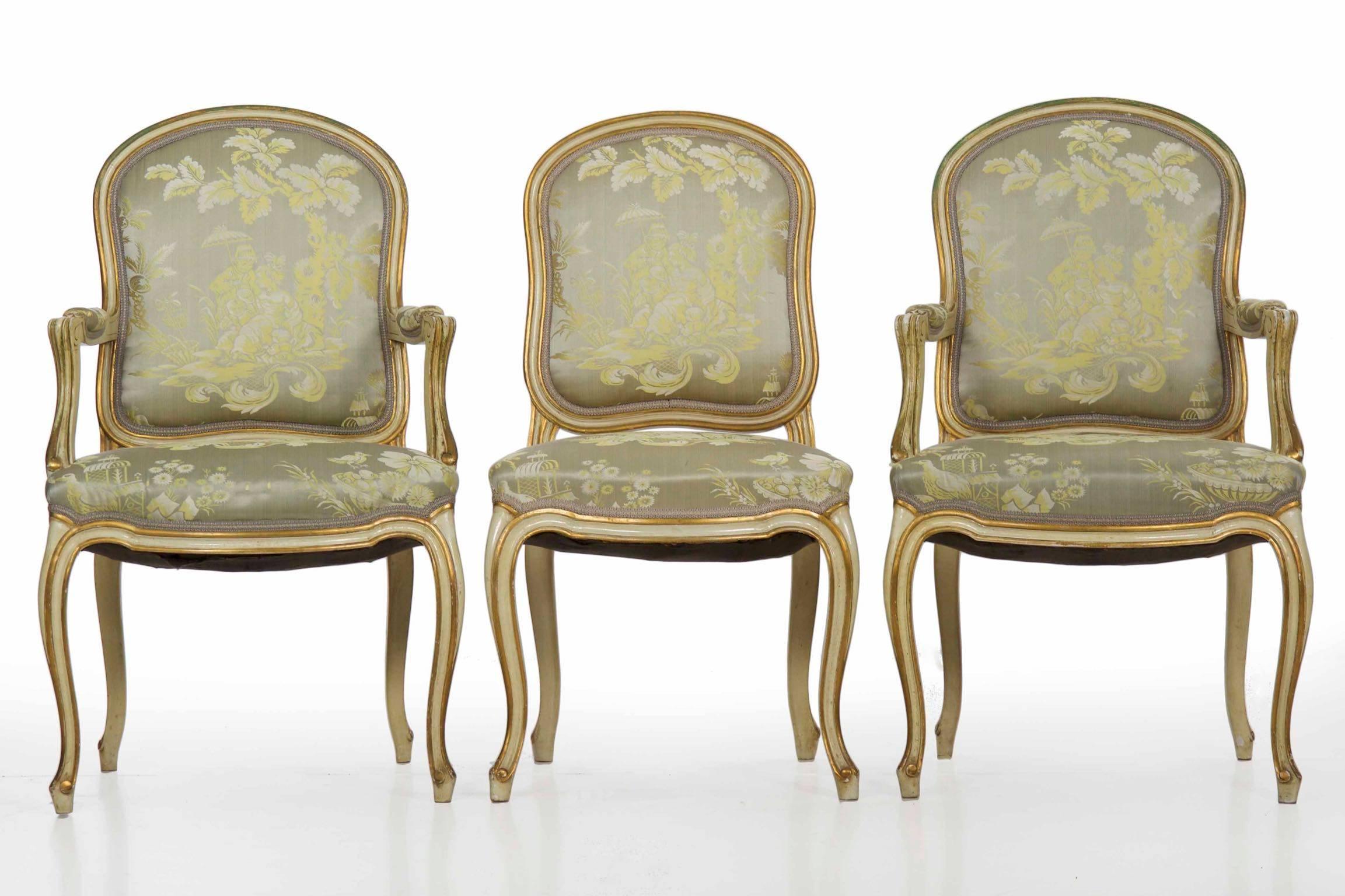 This gorgeous set of vintage French Louis XV style dining chairs is quite large, comprised of ten side chairs and two-arm chairs. They remain in excellent vintage condition with multiple layers of polychroming, showing brilliant jade, gilt and beige