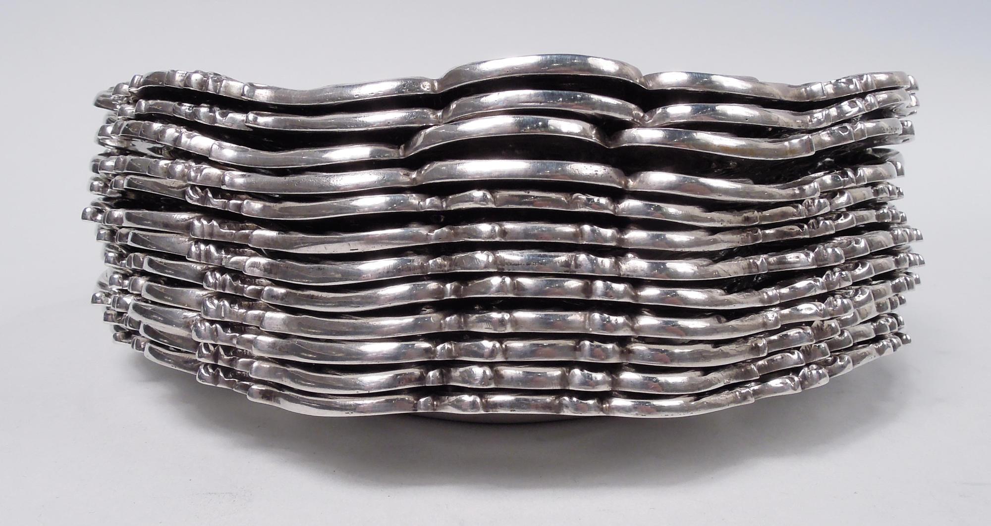 Set of 12 Chantilly sterling silver bread & Butter plates. Made by Gorham in Providence. Each: Plain and round serpentine well; tapering and chased shoulder with dynamic scrolls overlaid with garlands and strewn with flowerheads. Leafing scrolls
