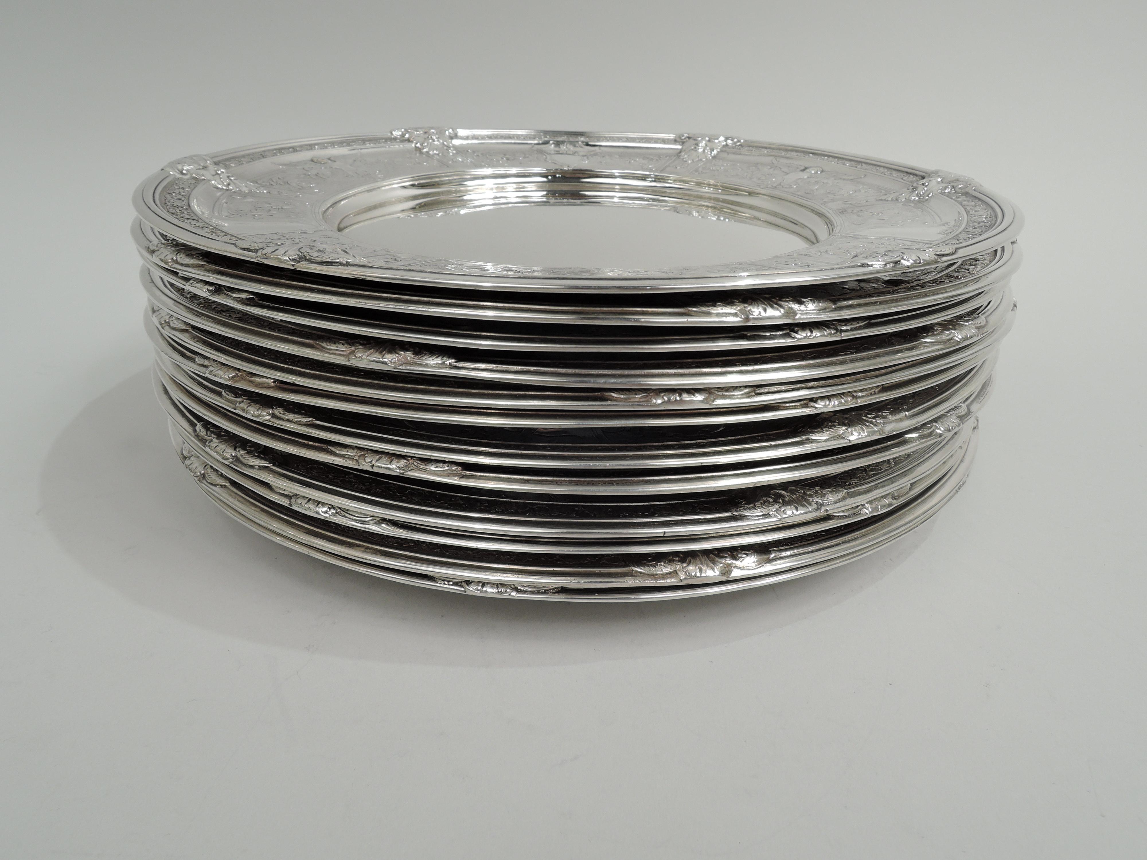 Set of 12 Florenz sterling silver dinner plates. Made by Gorham in Providence, 1926-9.
Each: round and plain well. Shoulder has rectilinear frames inset with chased Quattrocento ornament including griffins and foliate scrolls as well as armorial