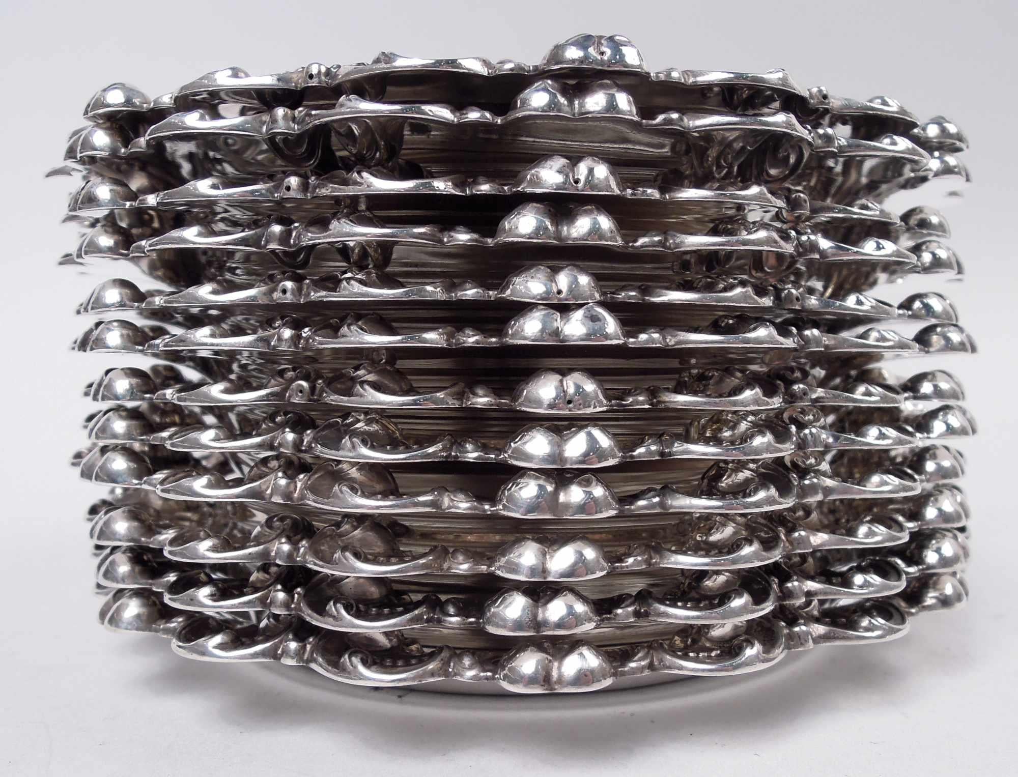 Set di 12 piatti classici vittoriani in argento sterling per pane e burro. Prodotto da Gorham a Providence nel 1899-1901. Ciascuno: Liscio e rotondo, con volute di foglie applicate e bordo a bocciolo. Monogram inciso. Completamente marcato con il