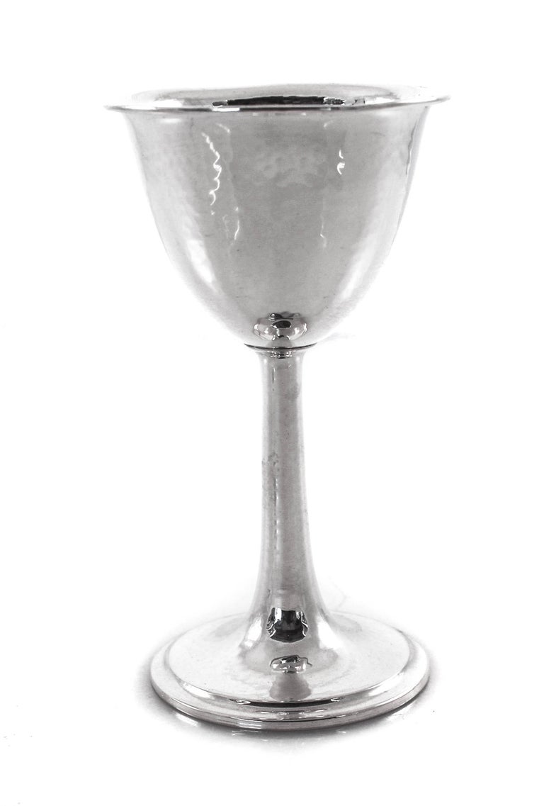 This set of 12 hammered goblets are done in the Arts & Crafts style that was at its peak in the early 1900s. Both in shape and pattern. Lovely next to each guests place setting on a dinner table.