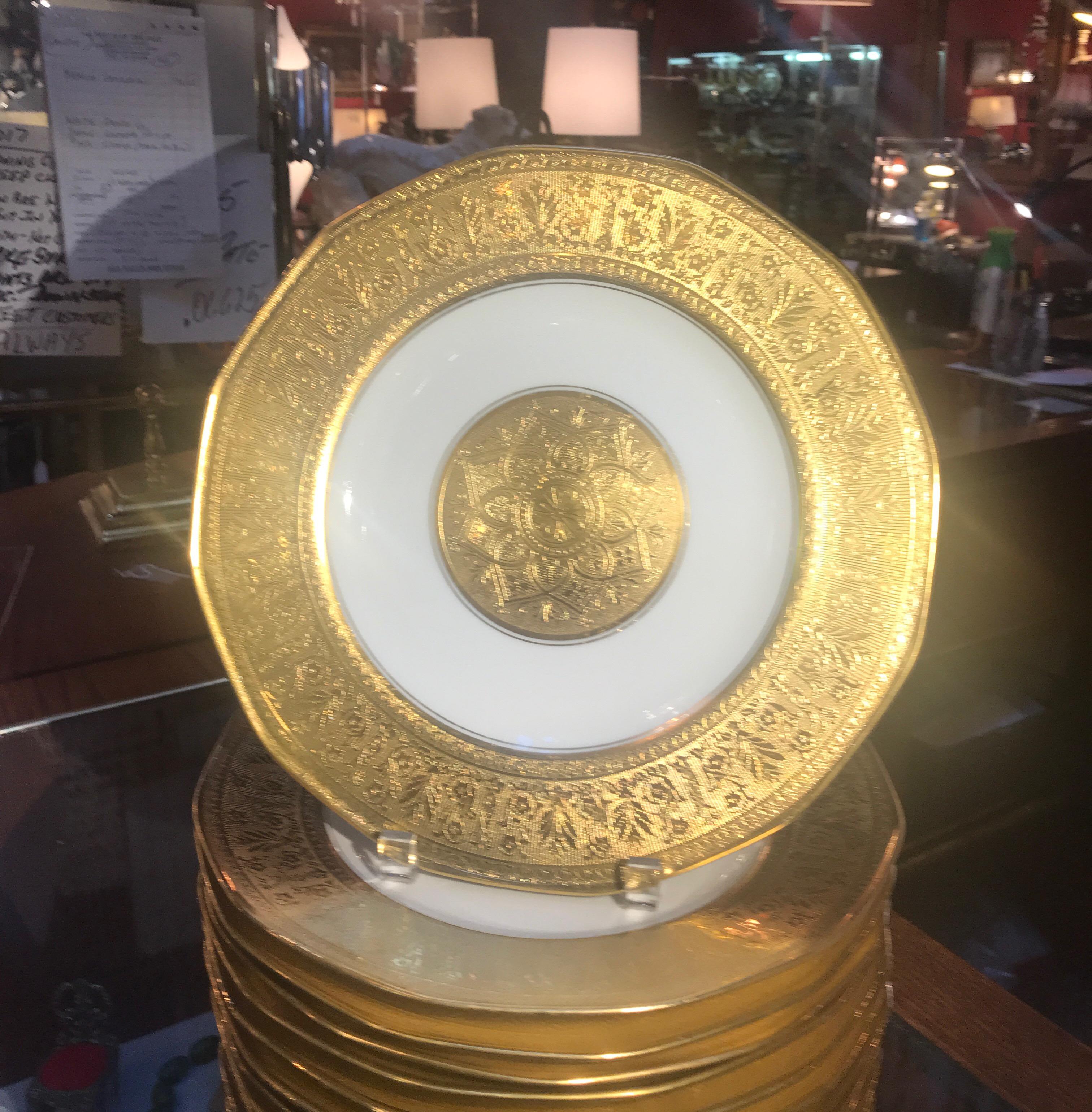 Luxurious set of 12 heavy gold encrusted service dinner plates by Theodore Haviland made in France. The set with wide god borders with a central medallion.