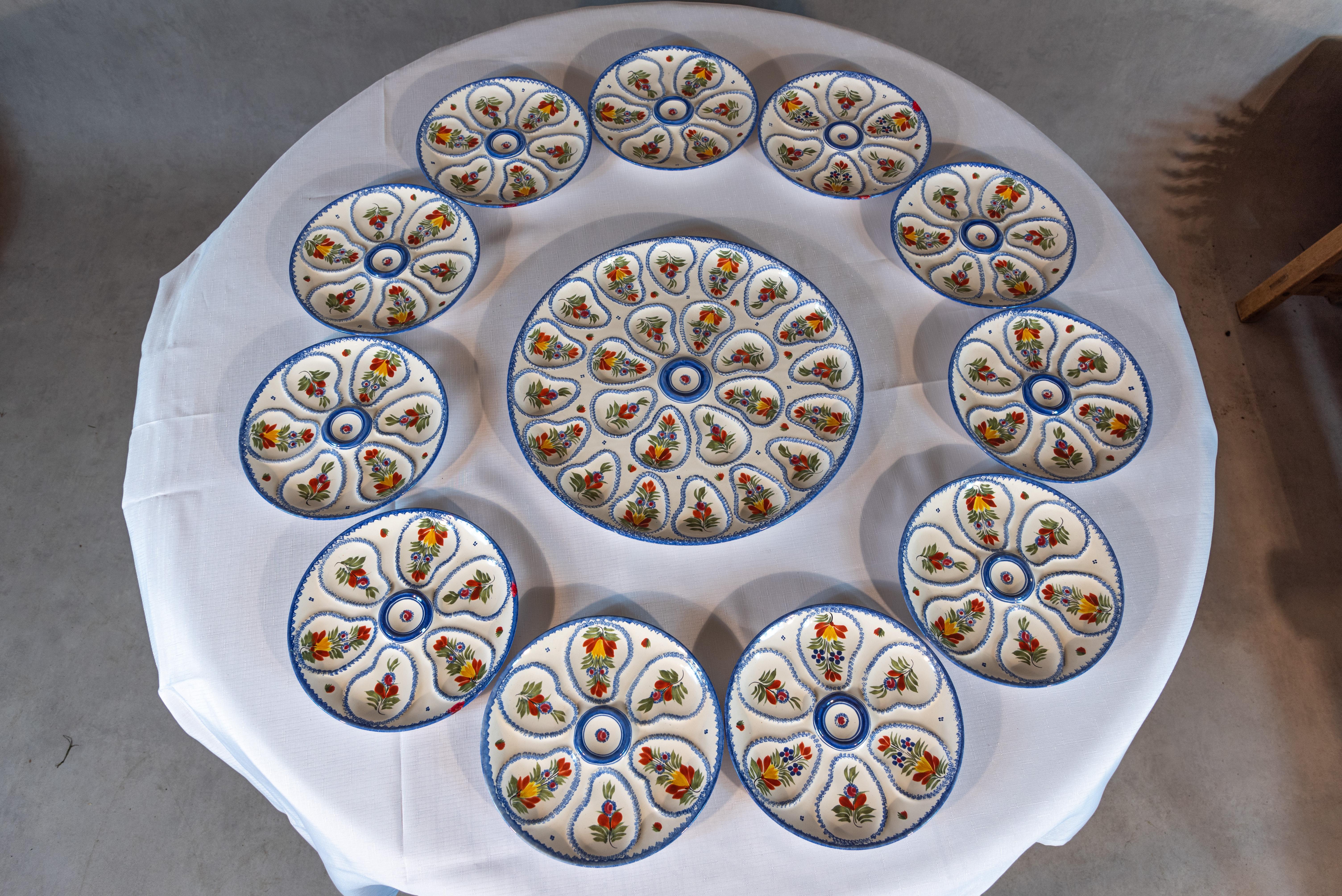 Cet ensemble de 12 assiettes à huîtres Henriot Quimper est un magnifique exemple de la beauté et du savoir-faire de la faïence de Quimper. Chaque assiette présente un motif unique et complexe peint à la main avec des couleurs vives et des motifs