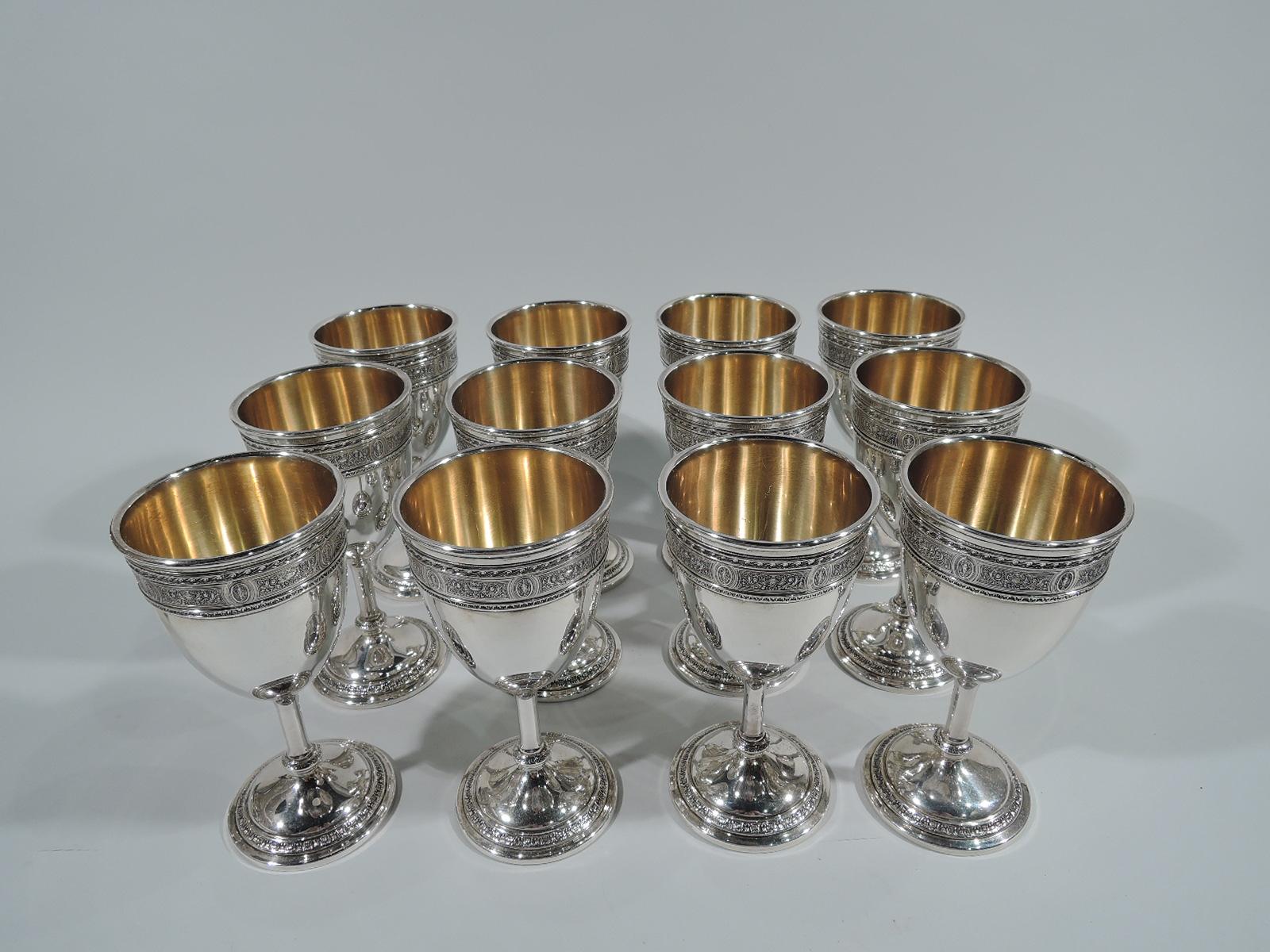 Set of 12 sterling silver goblets in Wedgwood pattern. Made by International in Meriden, Conn., circa 1920. Each: Ovoid bowl, cylindrical stem on knop, and stepped foot. Band of Neoclassical ornament, including paterae and amphorae, entwined with