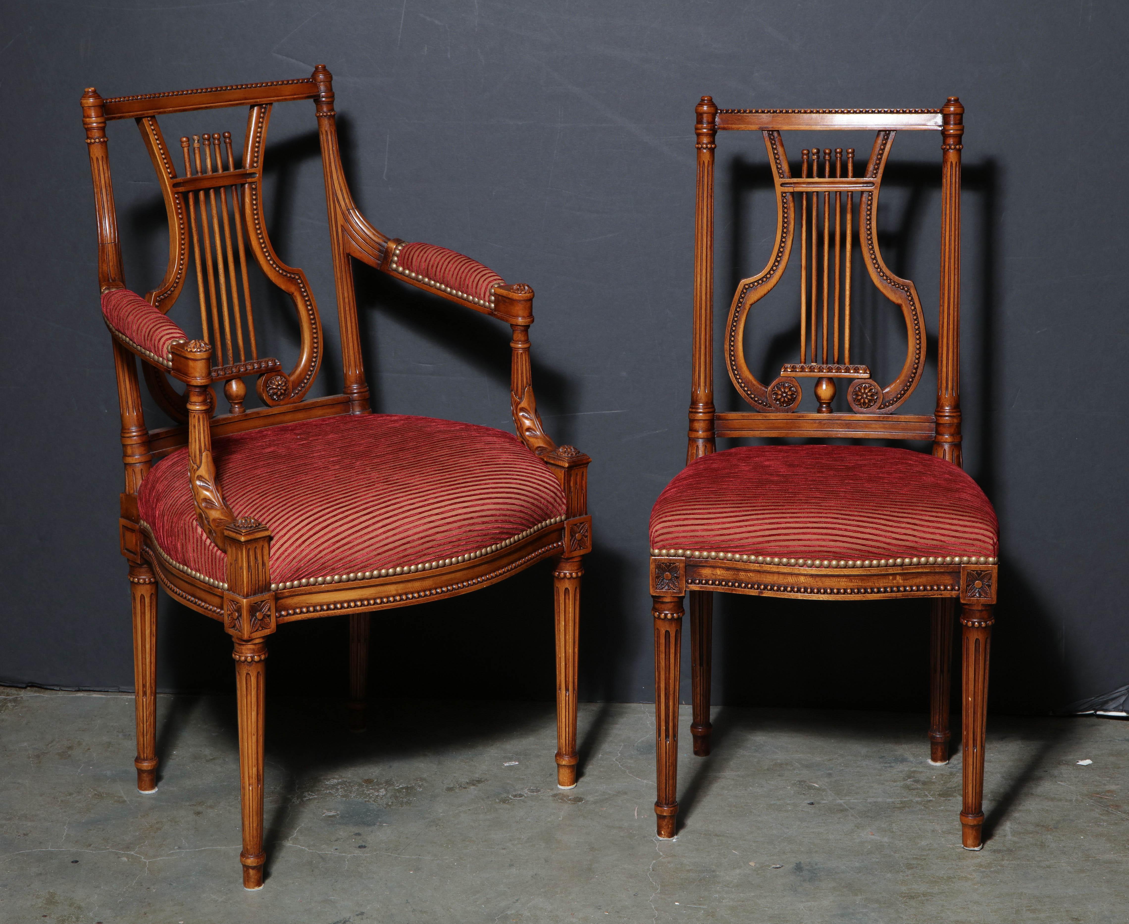 A fine set of 12 Louis XVI style carved mahogany dining chairs, with carved lyre form backrests, fluted supports, arms and legs and an upholstered padded cushion.