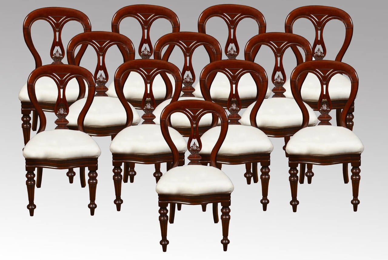 Set of 12 mahogany Victorian dining chairs the balloon back above carved splat to the seat having white upholstered drop in seats, raised up on turned reeded front supports.