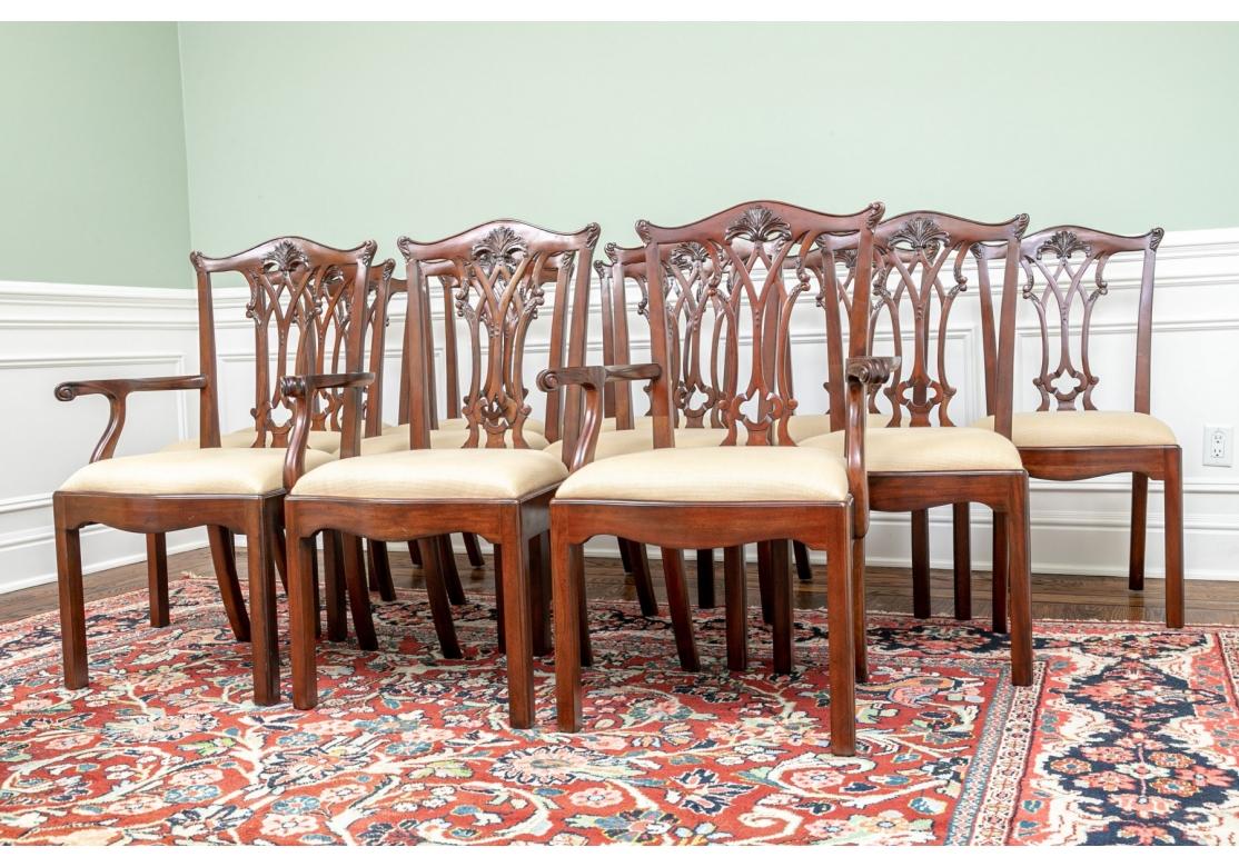 A fine and striking set of 12 Maitland-Smith, meticulously carved, Chippendale style mahogany dining chairs. Includes 10 side chairs and two end arm chairs. 
Featuring exquisitely carved and finished openwork back slats standing on four squared