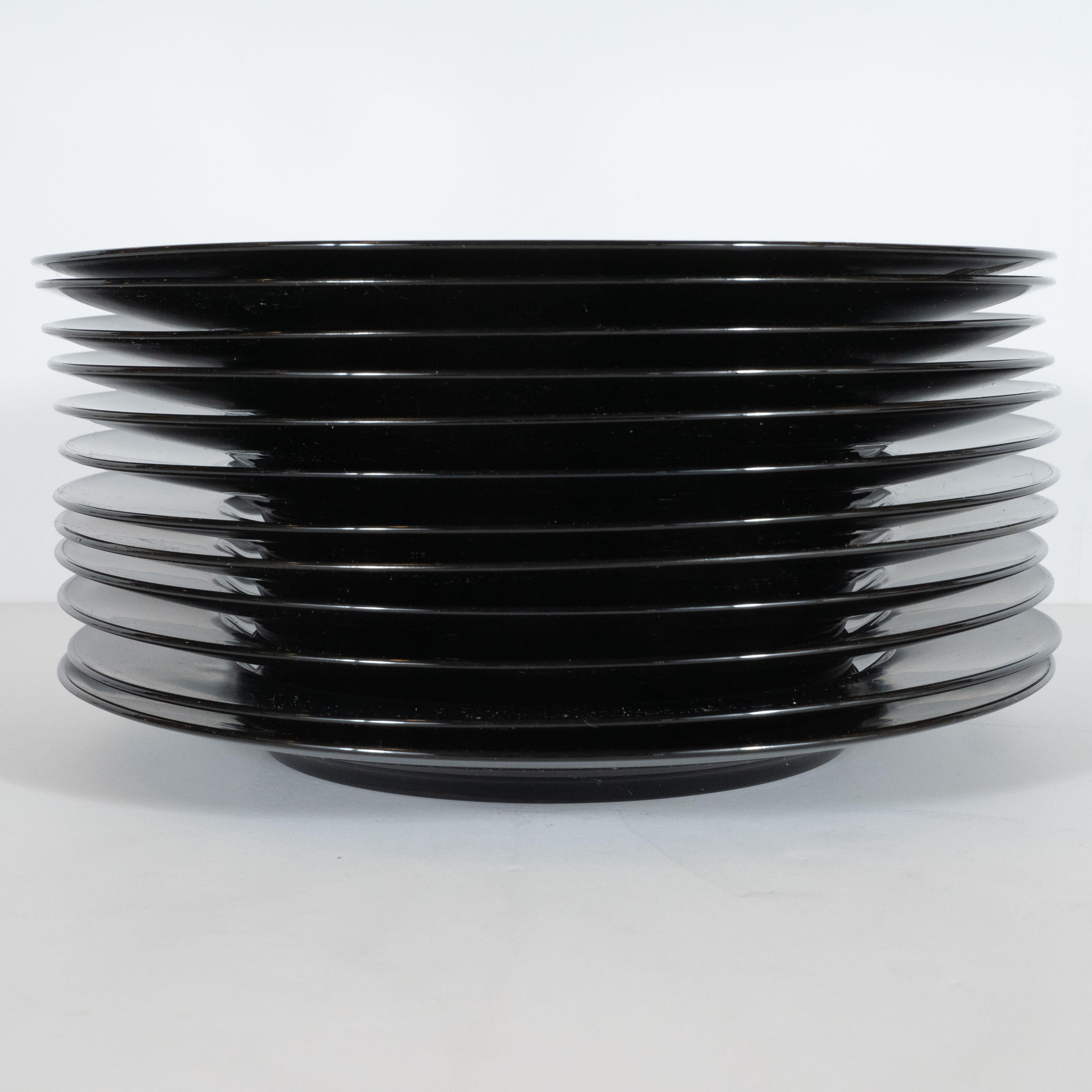 This set of 12 black porcelain Noir dinner plates was designed by Tapio Wirkkala for Rosenthal, circa 1970. Each round plate features a slim high-gloss lip, a wide rim rendered in Wirkkala's signature 