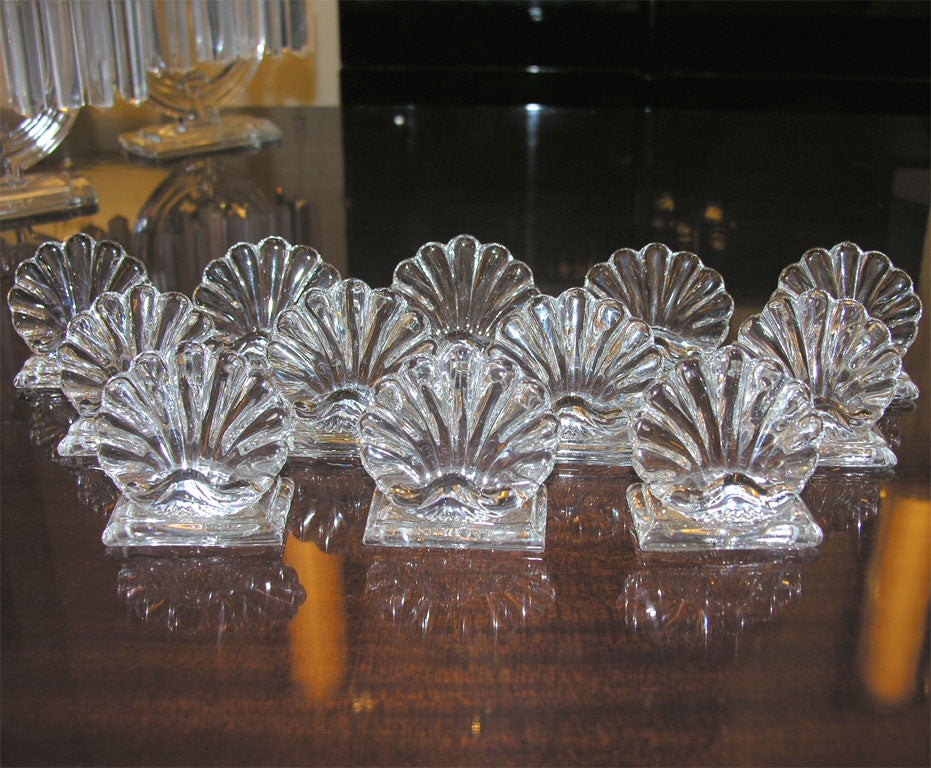 This stunning set of twelve place holders were created by Baccarat, one of the world's premiere makers of crystal since 1765- in France, circa 1960. They feature pentagonal volumetric bases with a scalloped back and a scallop shell form with an