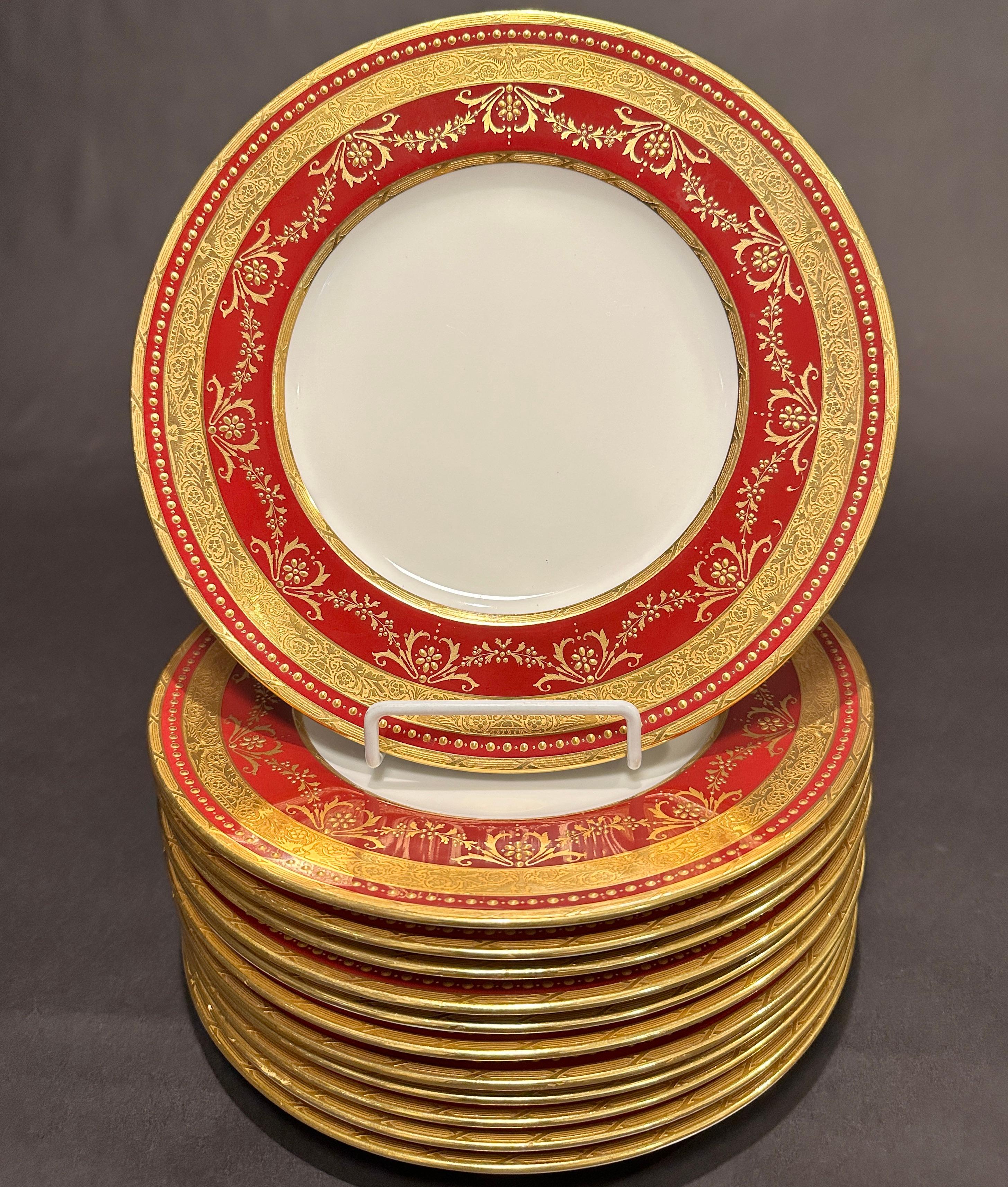 A set of 12 Minton top of the line burgundy bordered service plates with  raised paste gold decoration makes these exceptional. Twelve fabulous Minton dinner plates decorated with garlands of raised gold arabesque and raised gold jeweling. They have