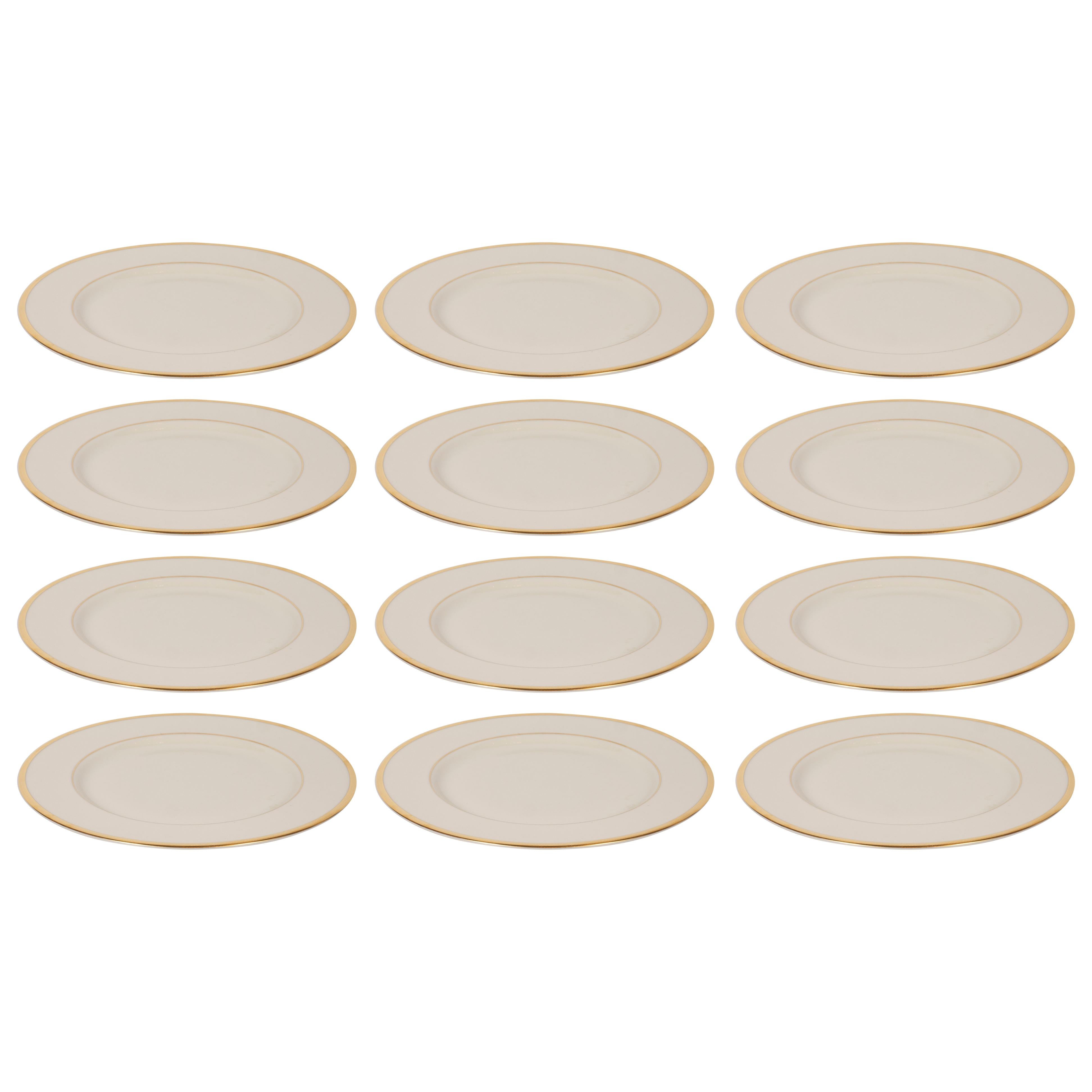 This elegant set of 12 dinner plates were realized by the esteemed maker Lenox in the United States. They feature 24-karat gold banding in the center, as well as along the outer perimeter on a bone china background. With their clean modernist lines